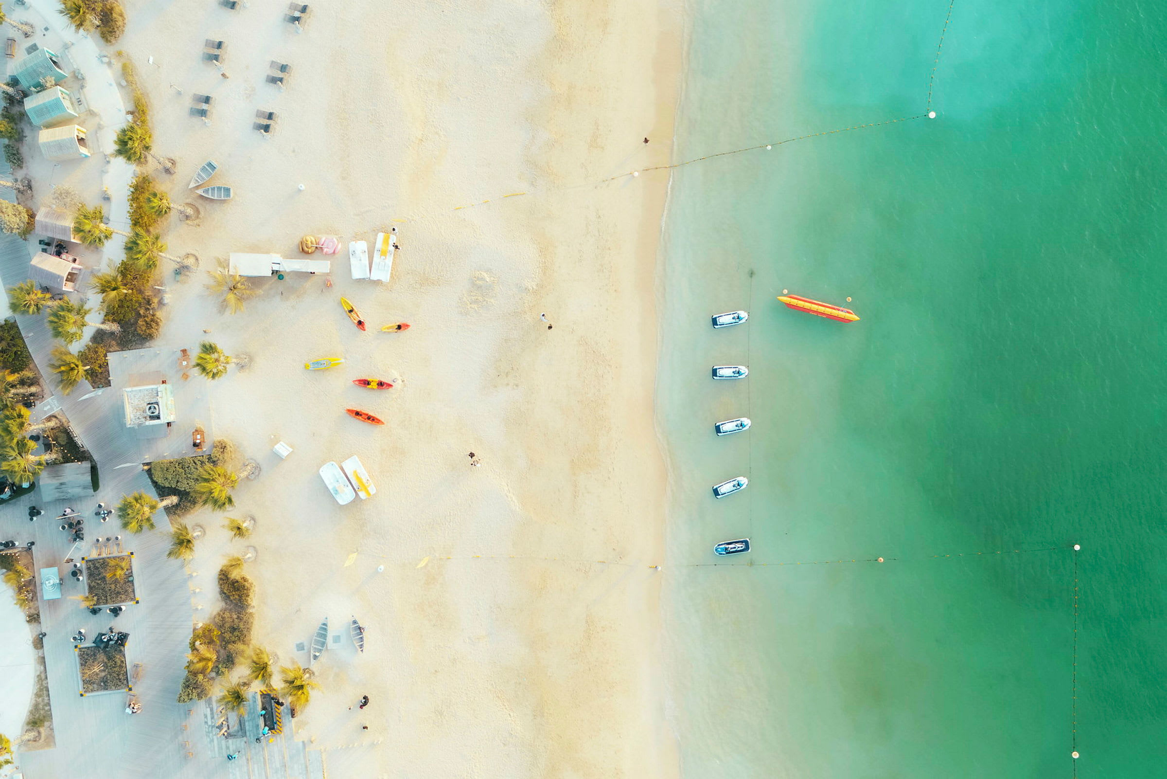 Flygfoto över en strand med båtar och kajaker vid vattnet. (AI-genererad text)