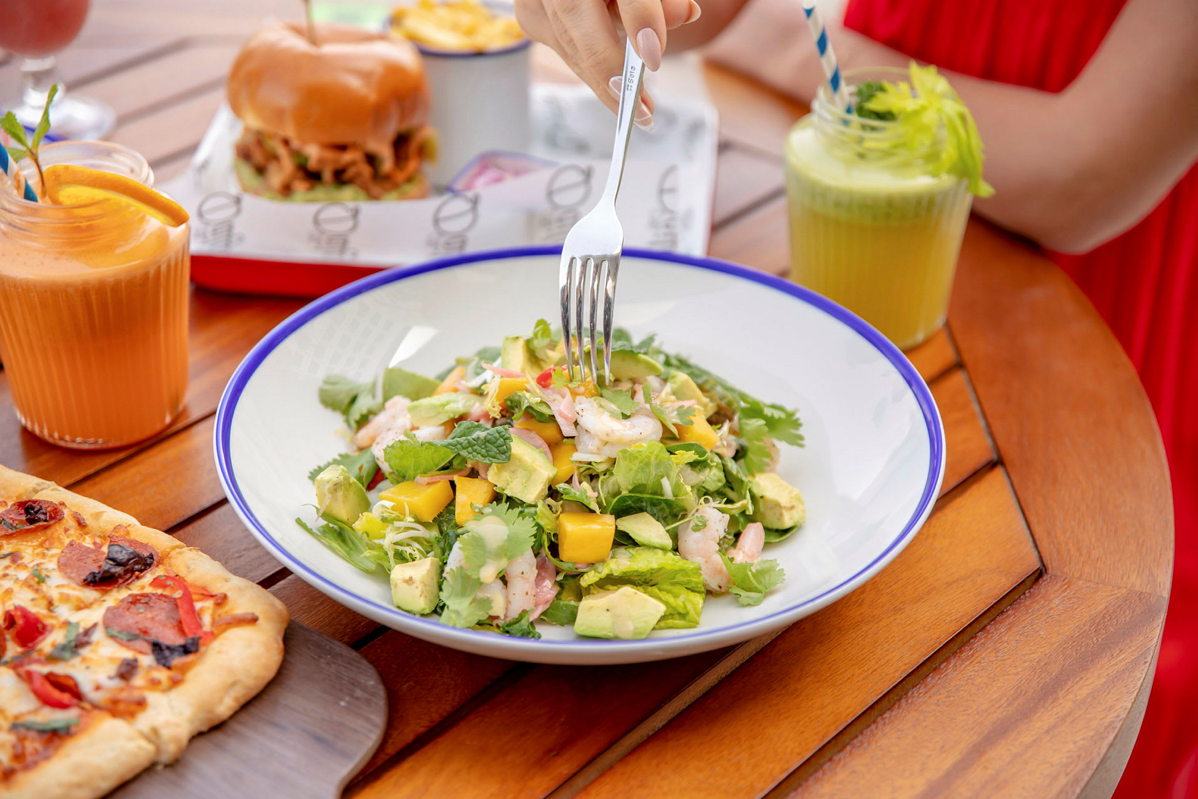 En tallrik med sallad, synlig på ett bord med olika maträtter och drycker. (AI-genererad text)