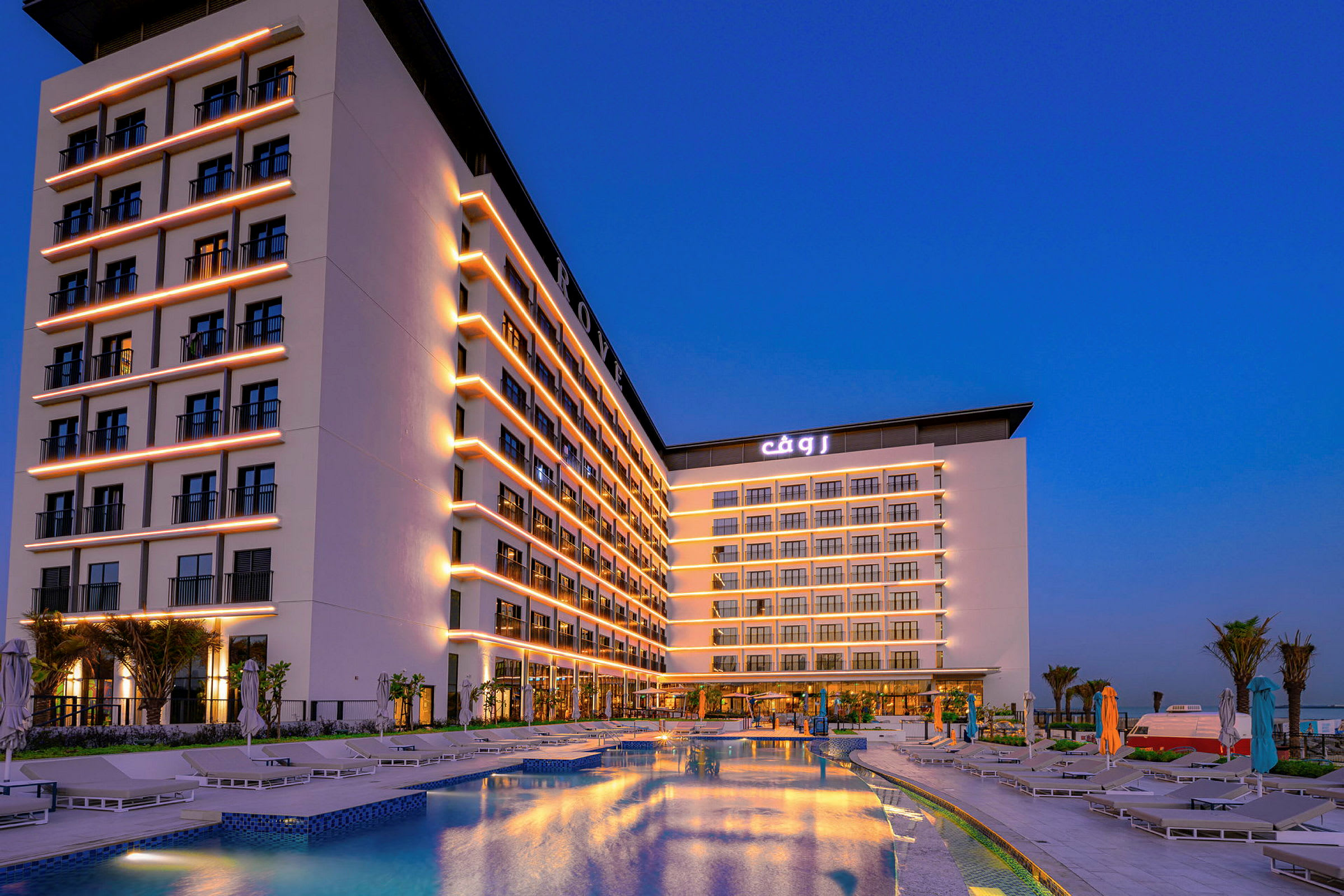 Hotellbyggnad med pool i förgrunden och kvällsupplysta fasader. (AI-genererad text)