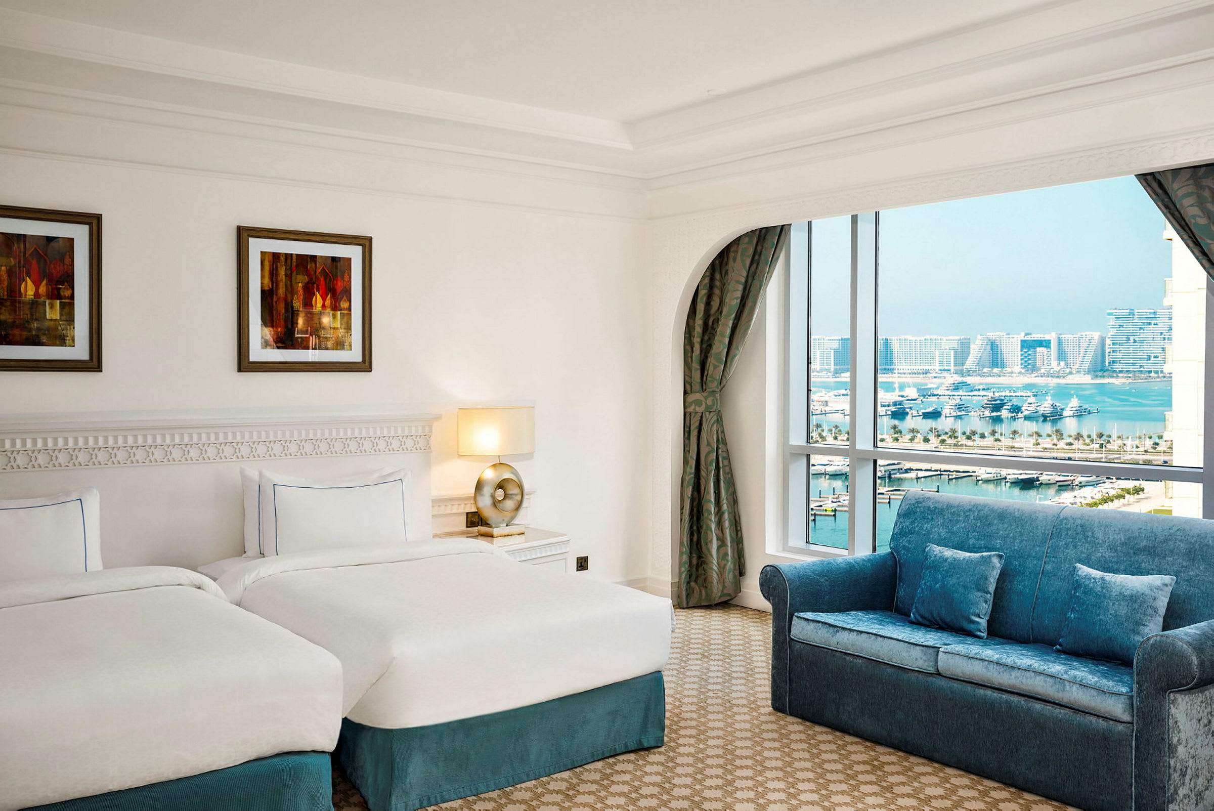 Ett hotellrum med två enkelsängar, en soffa och ett fönster med utsikt över en marina. (AI-genererad text)