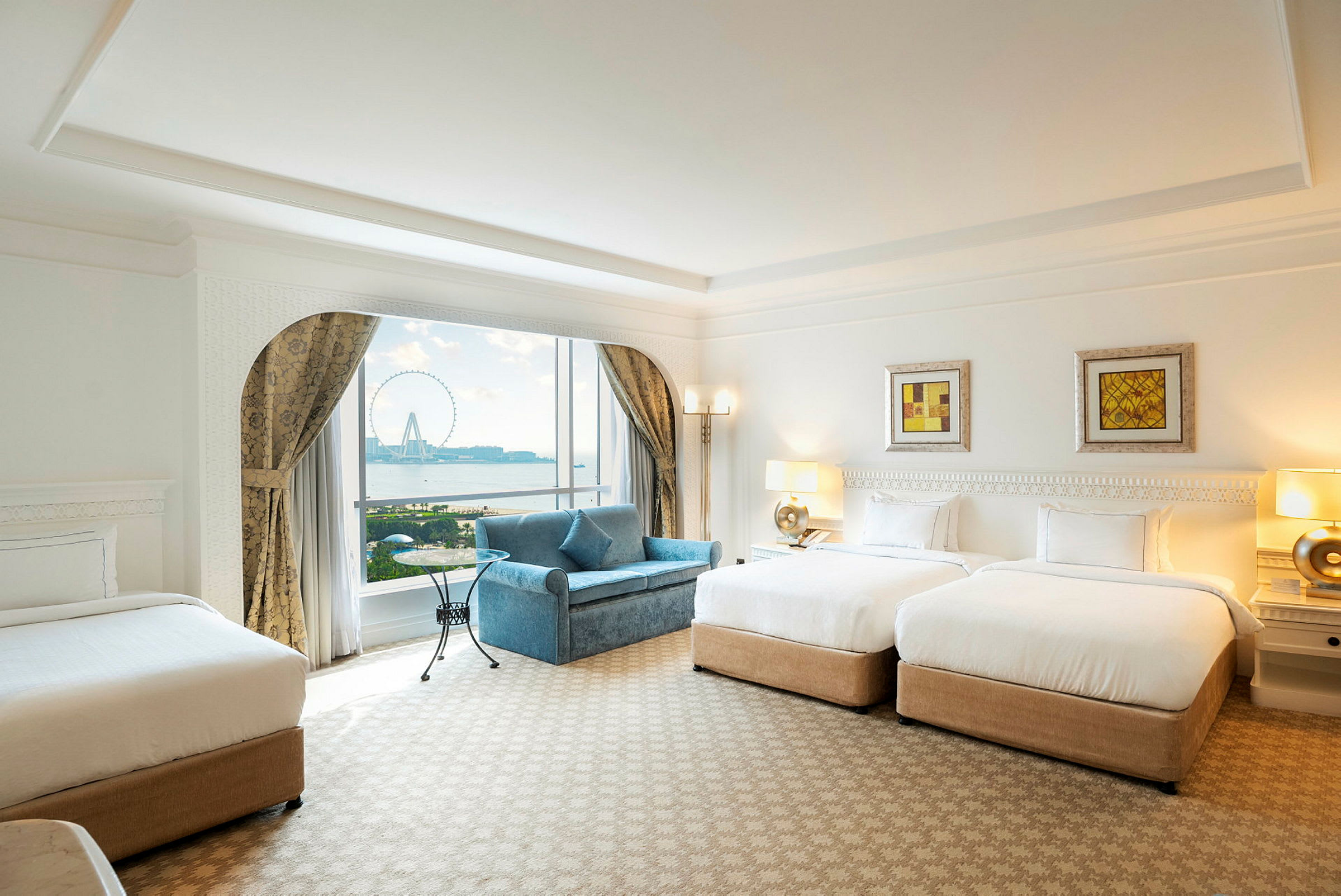 Ett hotellrum med två sängar, en soffa, och ett stort fönster som visar utsikten över ett pariserhjul. (AI-genererad text)