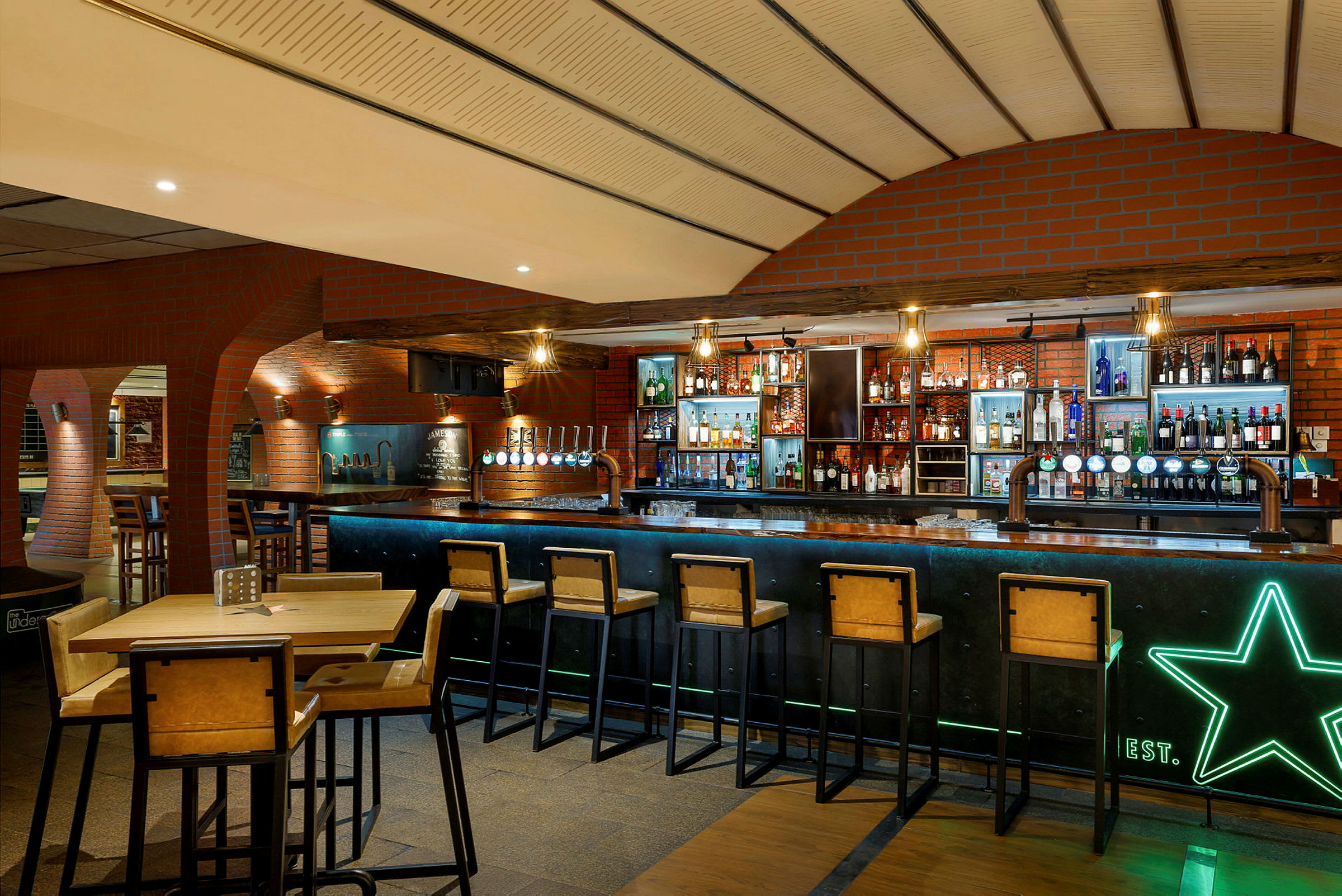 En bar med flera sittplatser och ett välfyllt utbud av flaskor och tappkranar. (AI-genererad text)