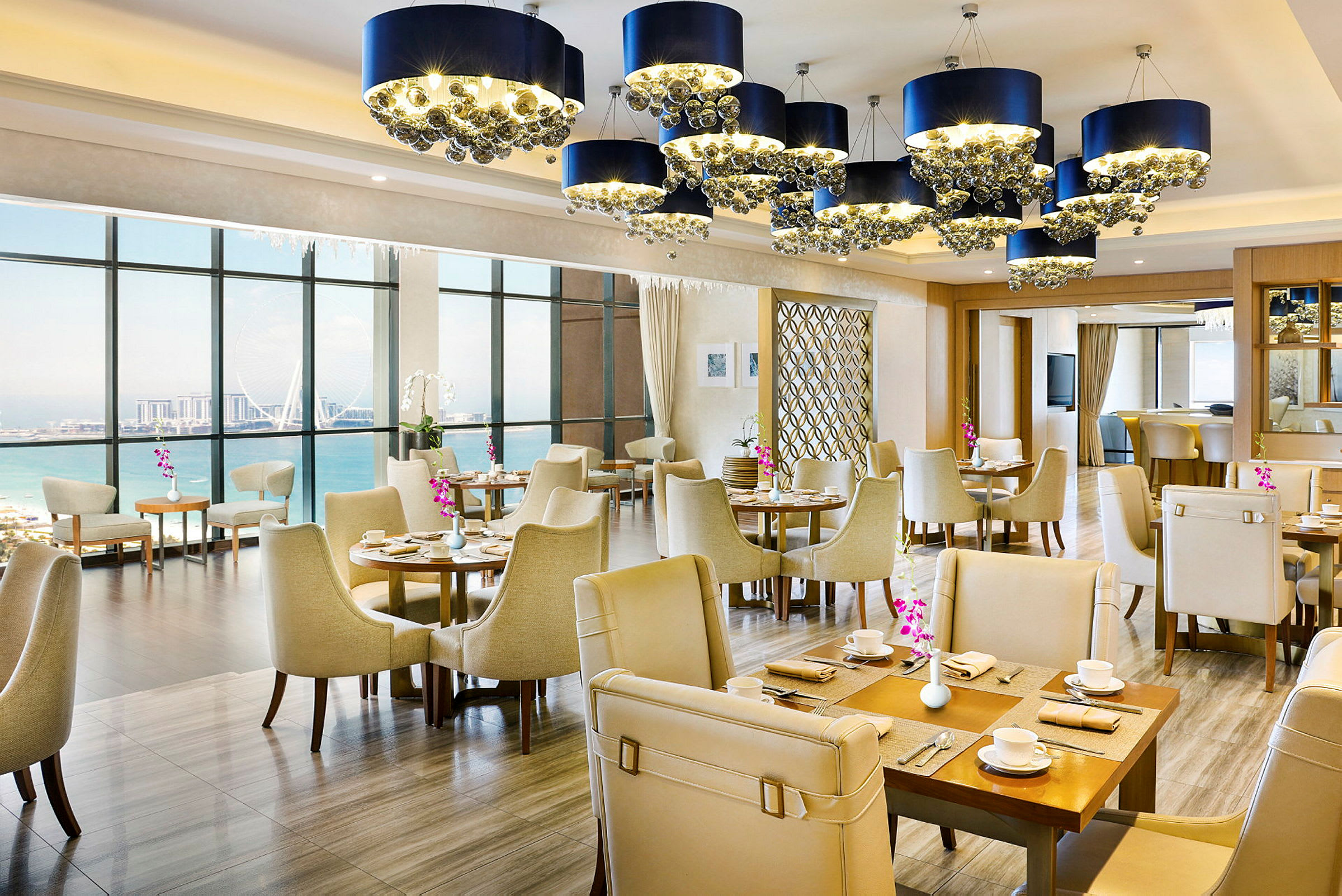 Interiören av en restaurang med eleganta möbler och fönster som vetter mot havet. (AI-genererad text)