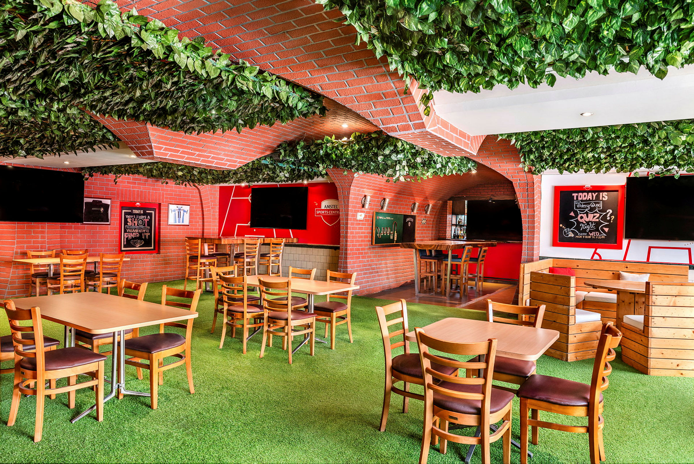 En interiör av en livlig restaurang med gröna väggar och tak. Trämöbler och en bar är inredda med röda tegelstenar. (AI-genererad text)