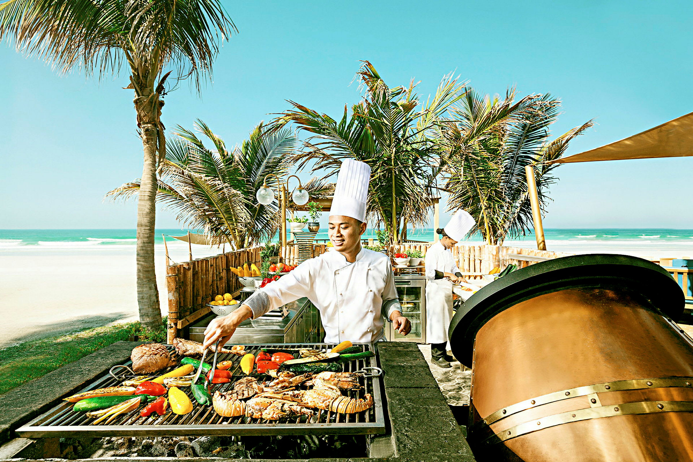 En kock vid en grillstation intill stranden med palmer i bakgrunden. (AI-genererad text)