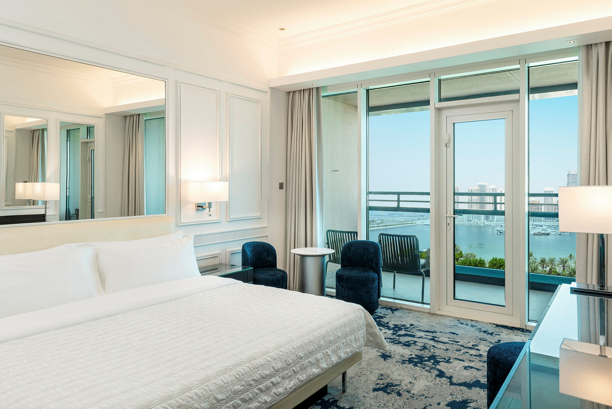 Hotellrum med bäddad säng, modern inredning och balkong med utsikt över havet. (AI-genererad text)