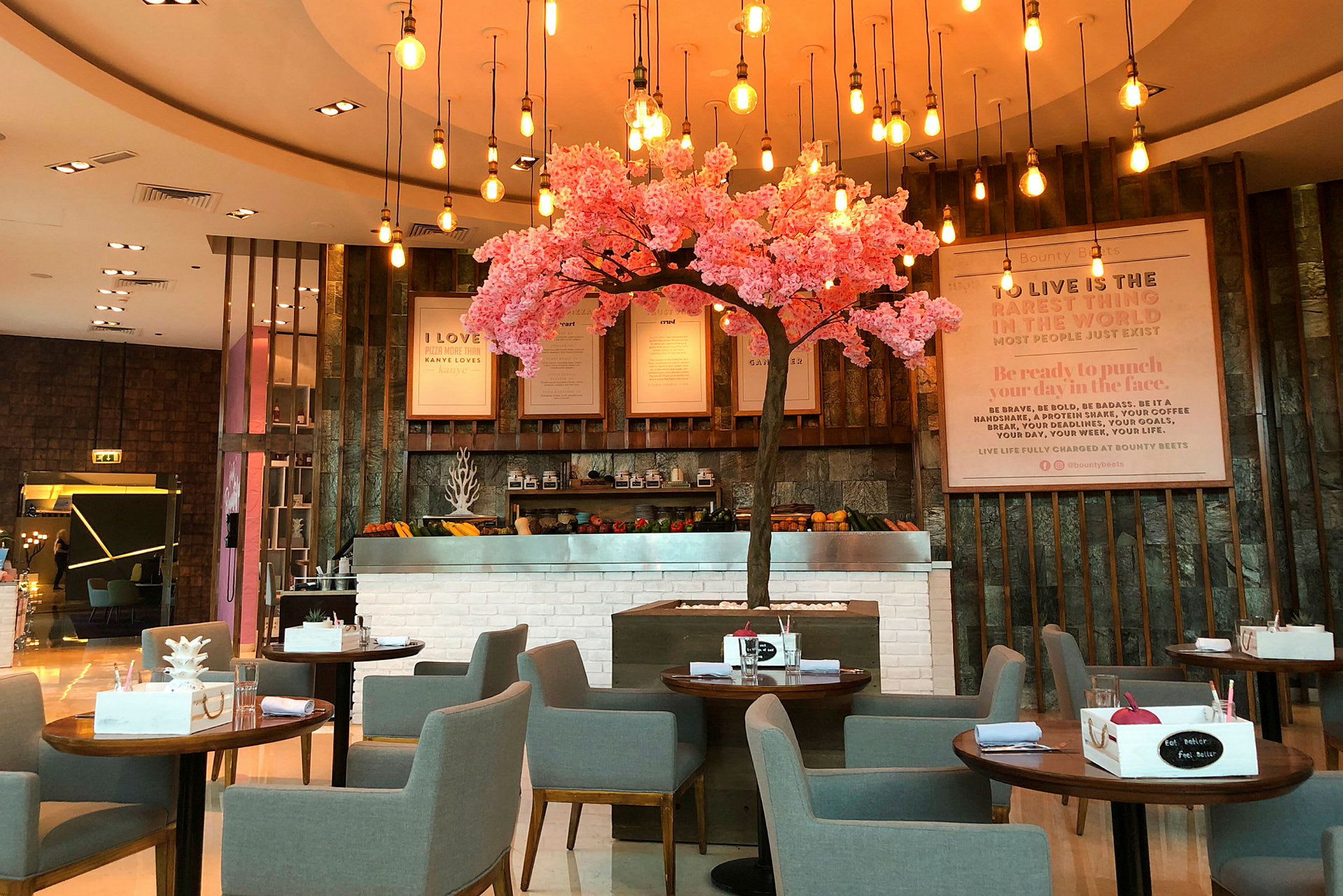 En restaurang med grå stolar och bord, en dekorativ rosa blommande träd i mitten. (AI-genererad text)