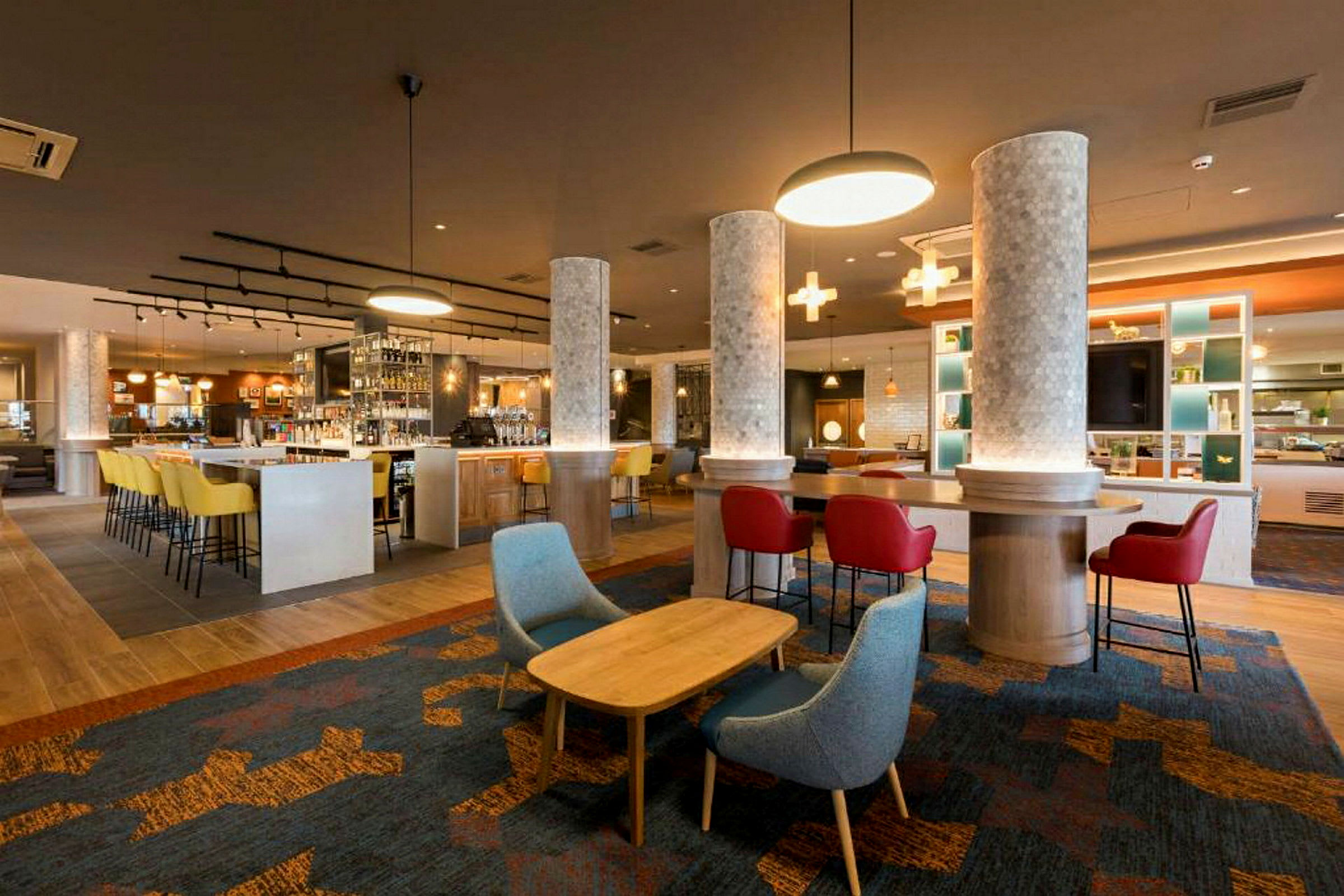En modern hotellbar med färgglada stolar och belysning. (AI-genererad text)