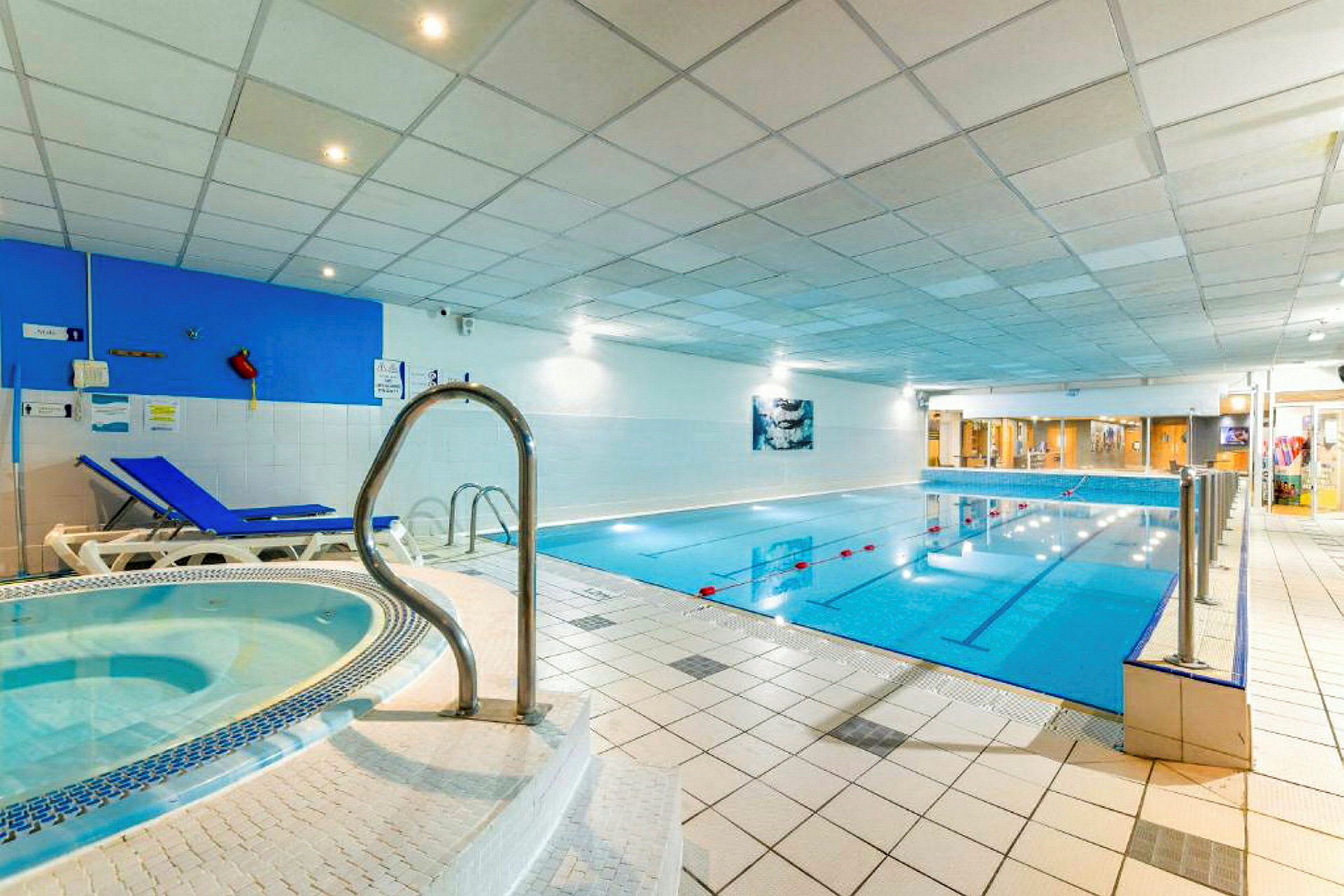 Inomhuspoolområde med en jacuzzi och solstolar. (AI-genererad text)