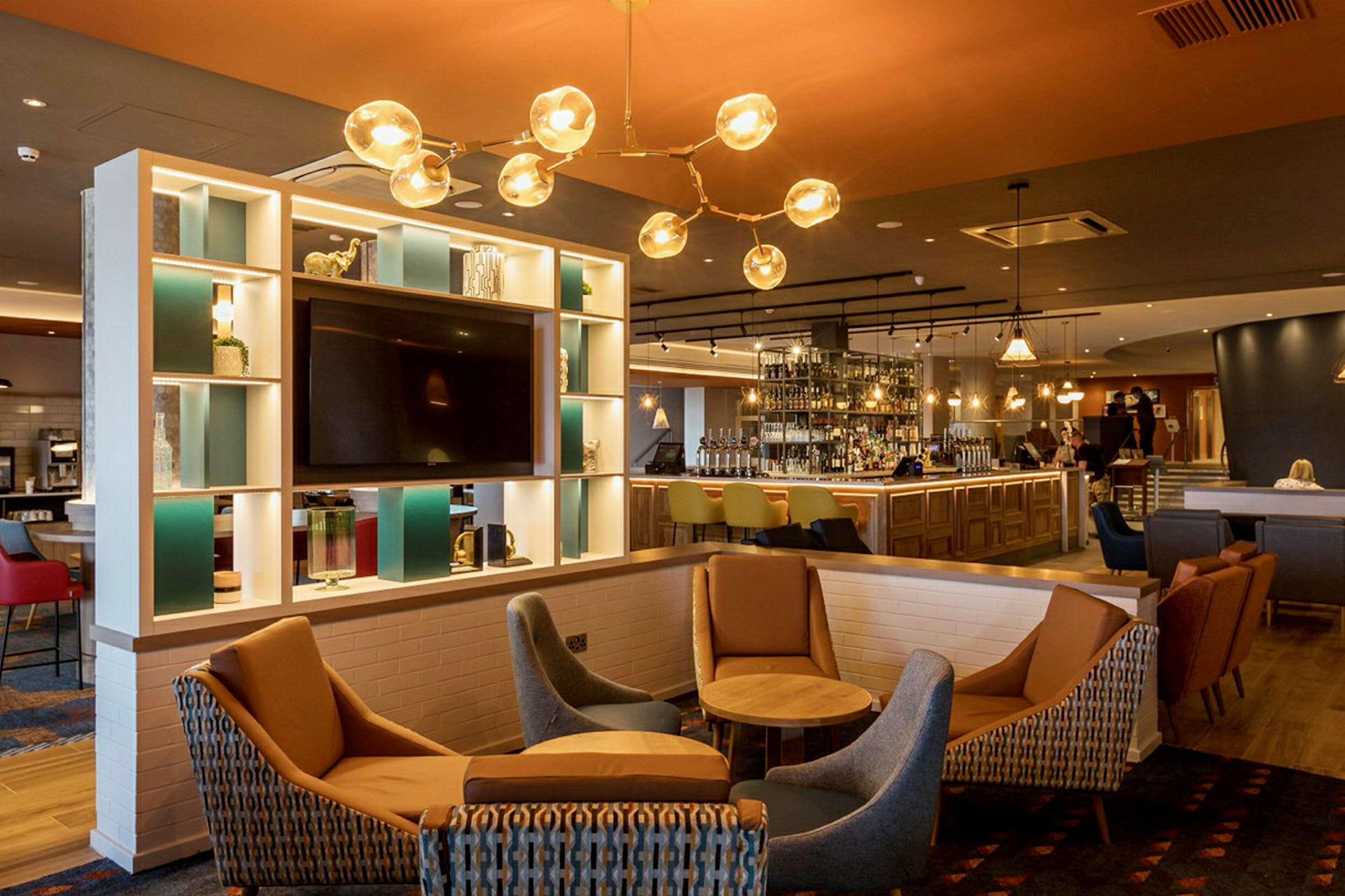Ett modernt hotellområde med en bar, sittplatser och inredning i ljusa färger. (AI-genererad text)