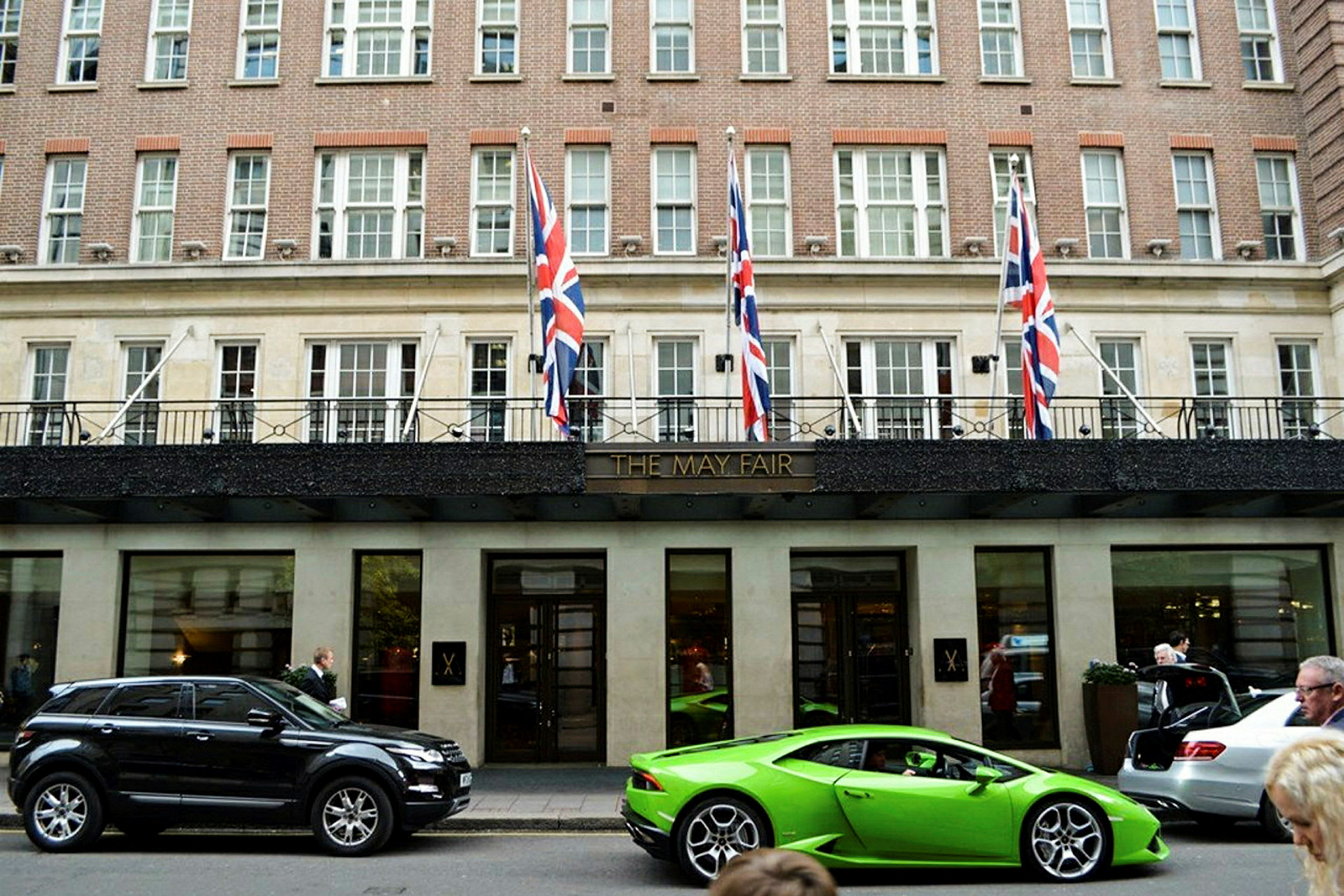 Fasad av det eleganta May Fair Hotel med bilar parkerade framför. (AI-genererad text)