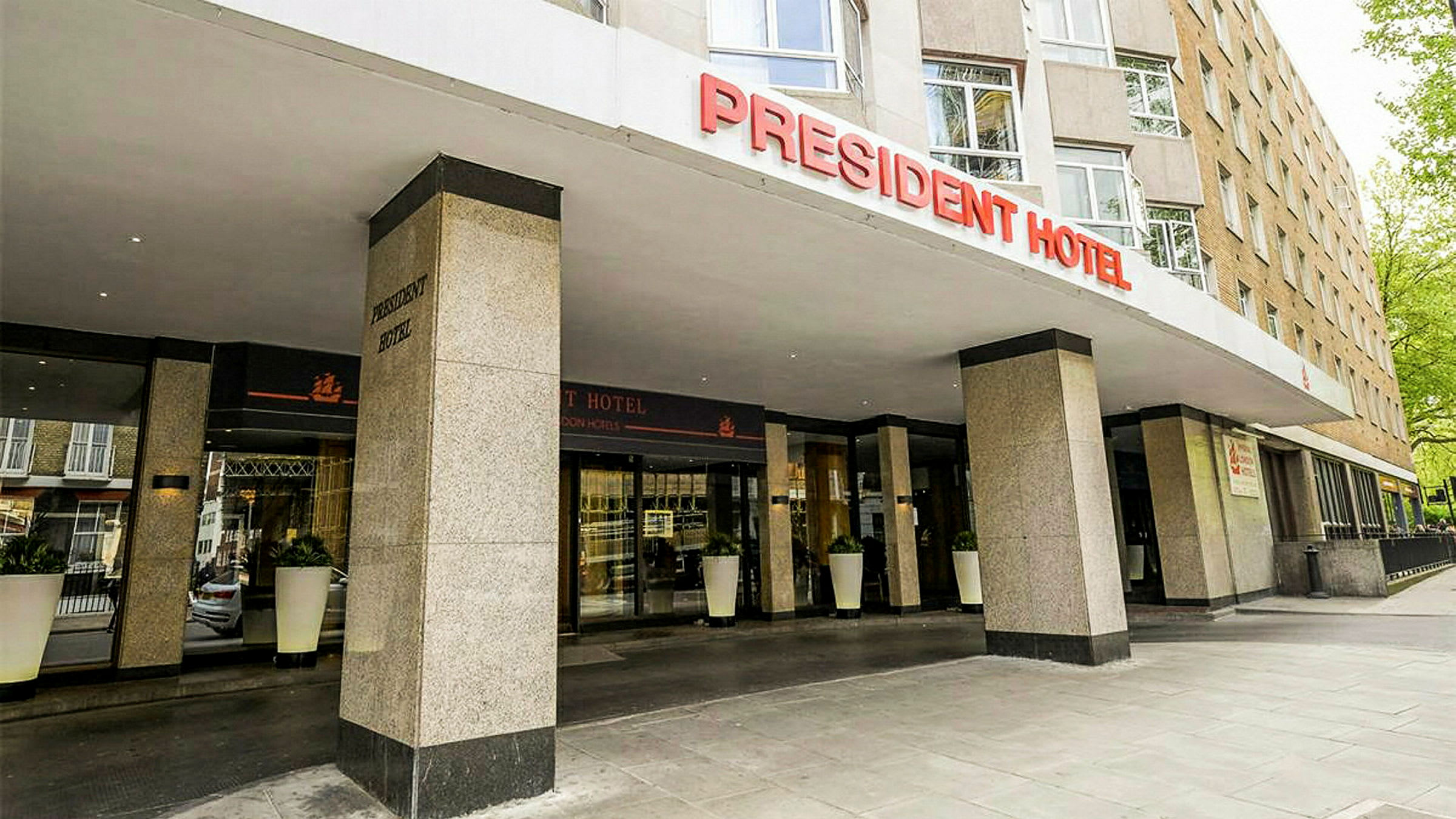 Framsidan av President Hotel med ingång och skylt. (AI-genererad text)