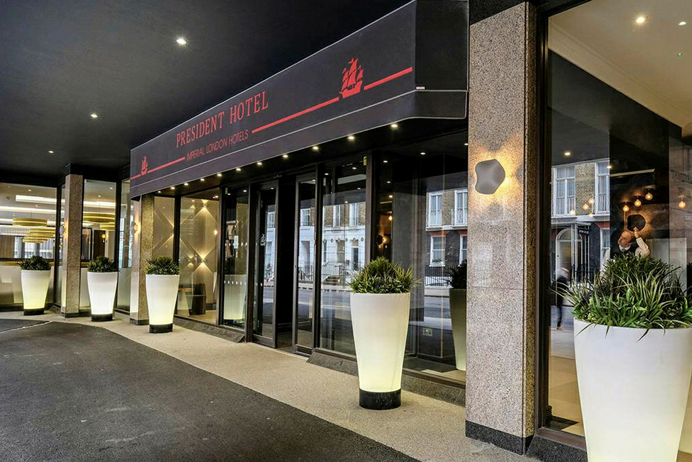 Entrén till President Hotel, med stora vita blomkrukor. (AI-genererad text)