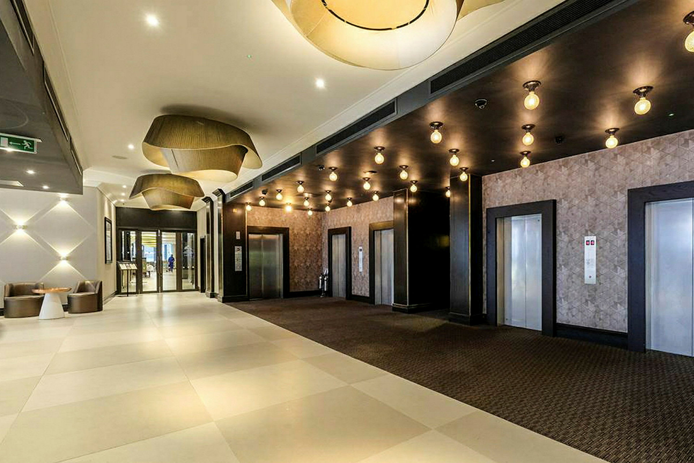 Hotellobby med tre hissdörrar och moderna armaturer. (AI-genererad text)