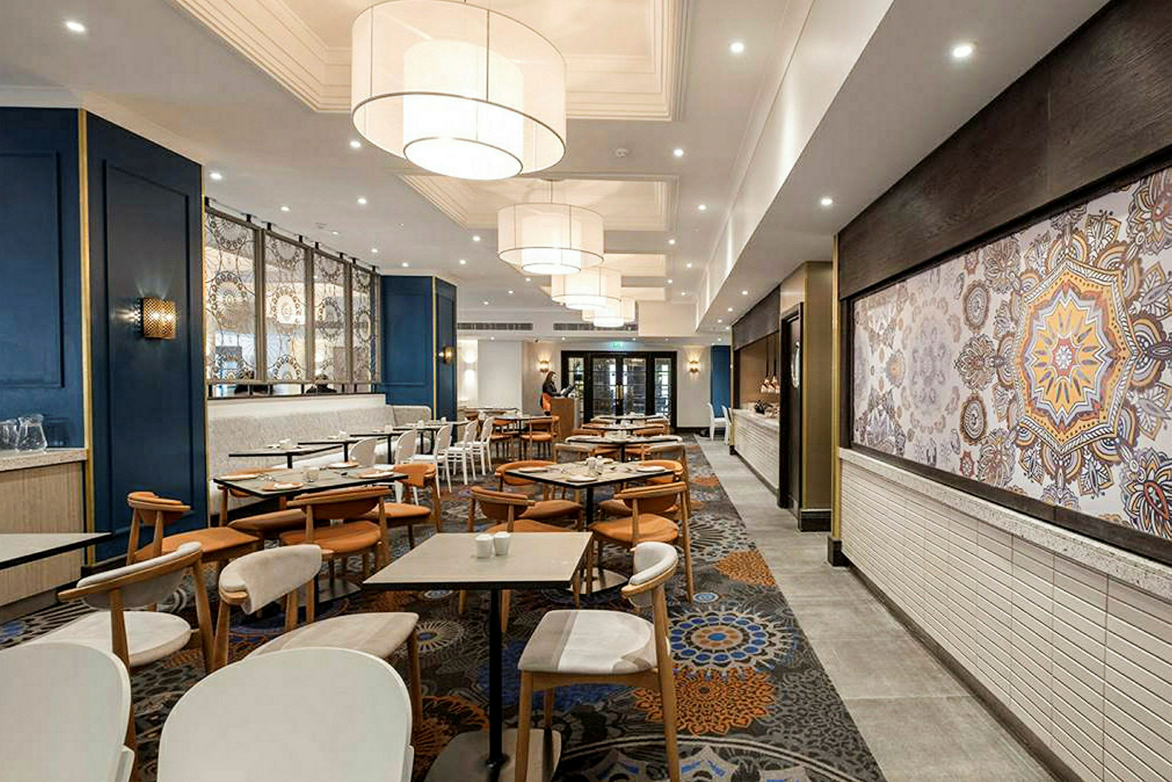 En restaurang med bord och stolar, modern inredning och stora lampor i taket. (AI-genererad text)