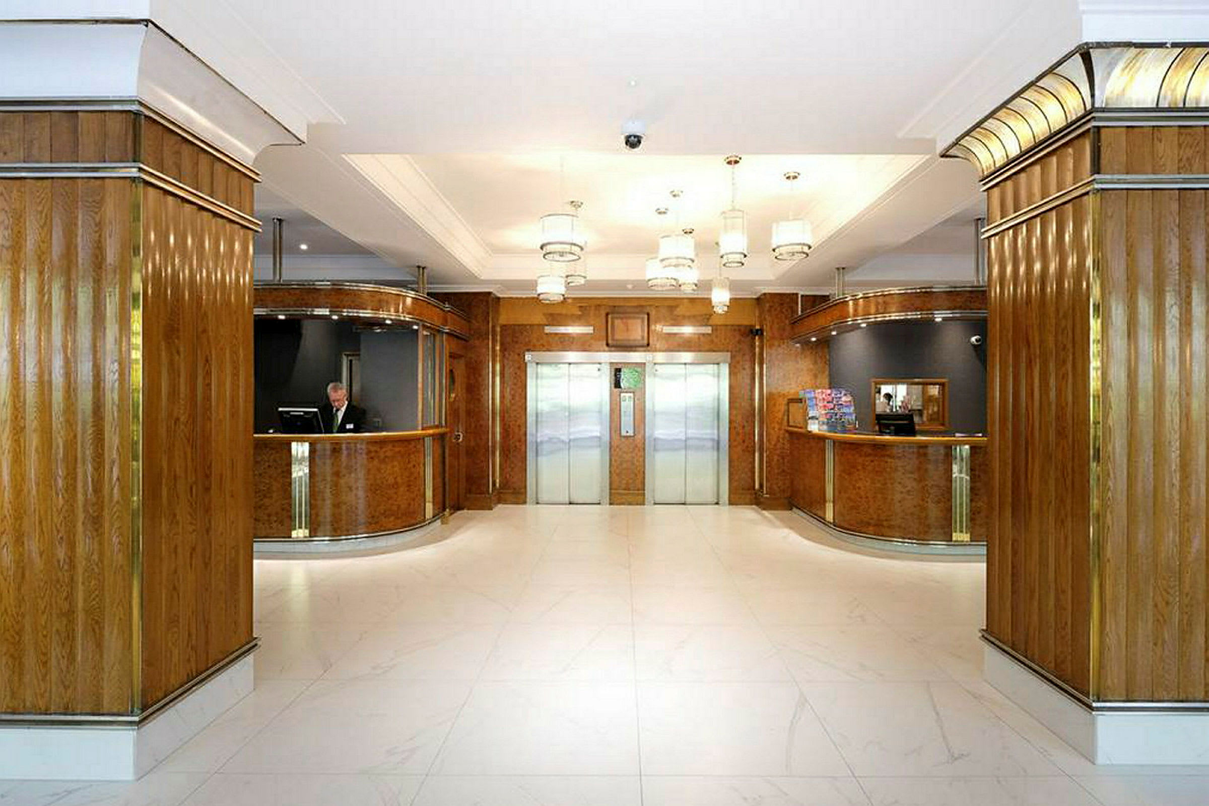 Hotellobby med hissar i mitten och receptioner på båda sidor. (AI-genererad text)