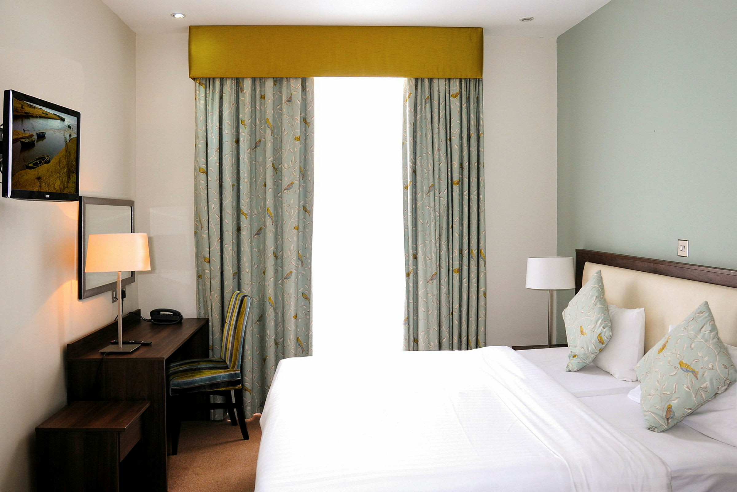 Ett hotellrum med en säng, skrivbord och fönster. (AI-genererad text)