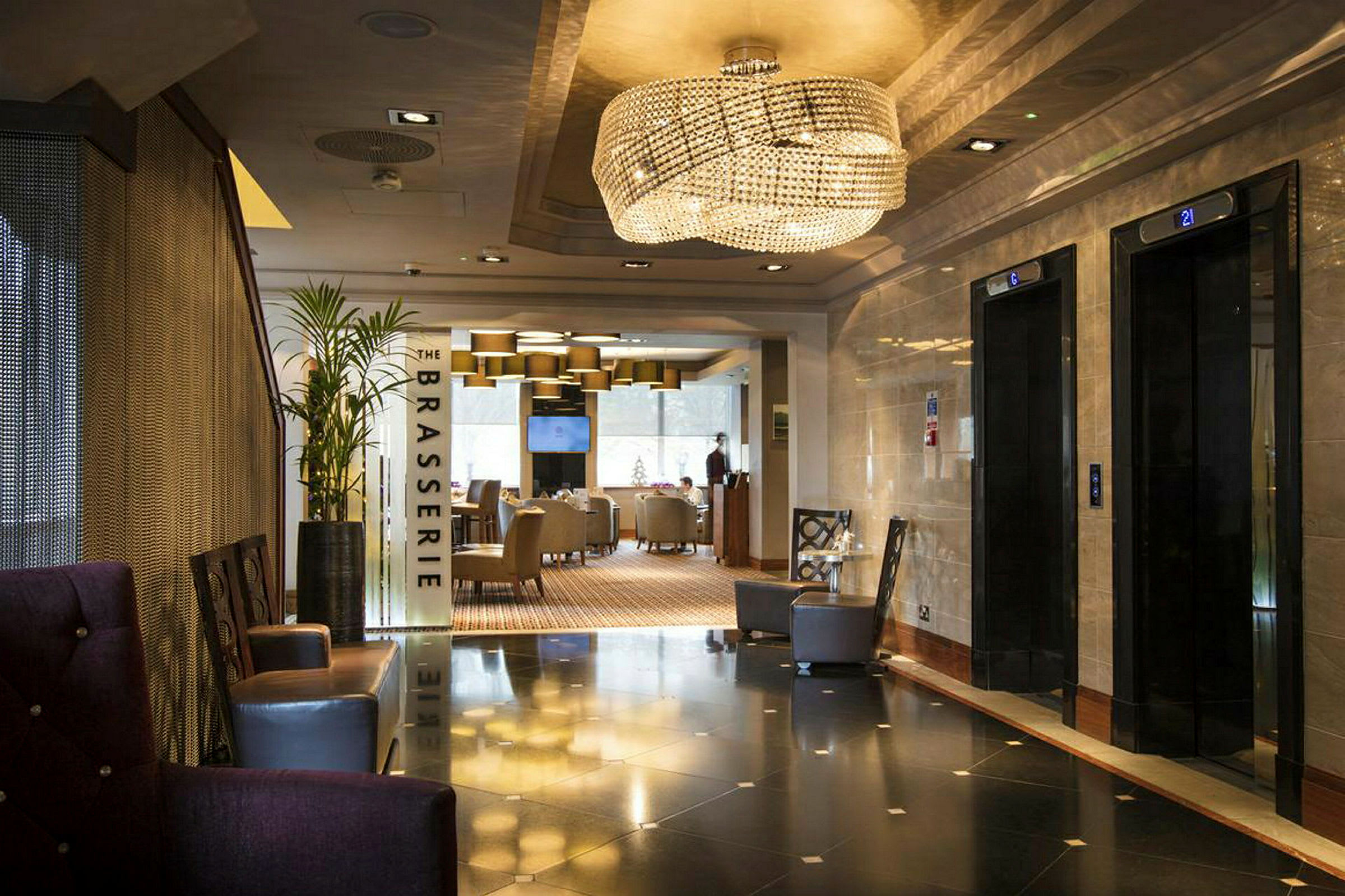 Hotellobby med hissar till höger och ingång till restaurangen 'The Brasserie' rakt fram. (AI-genererad text)