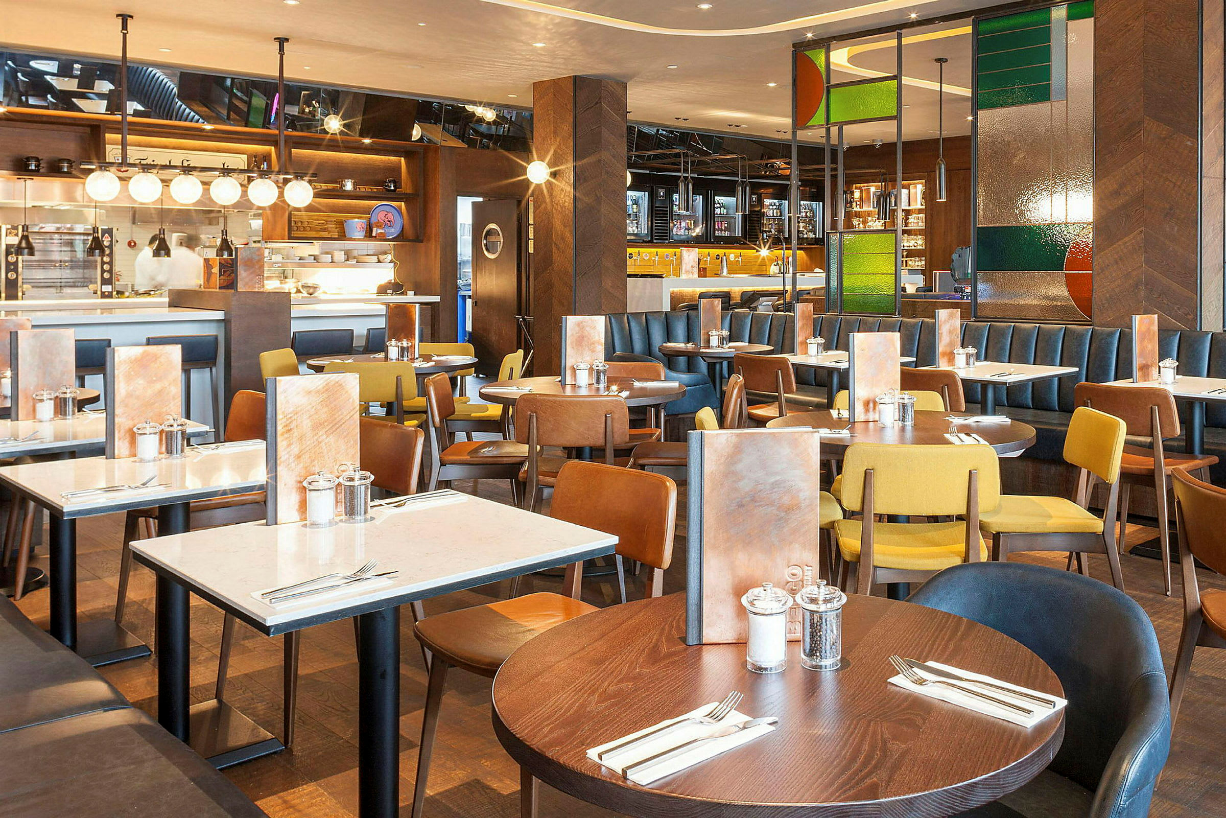 Restaurang med flera matbord och stolar i olika färger. (AI-genererad text)