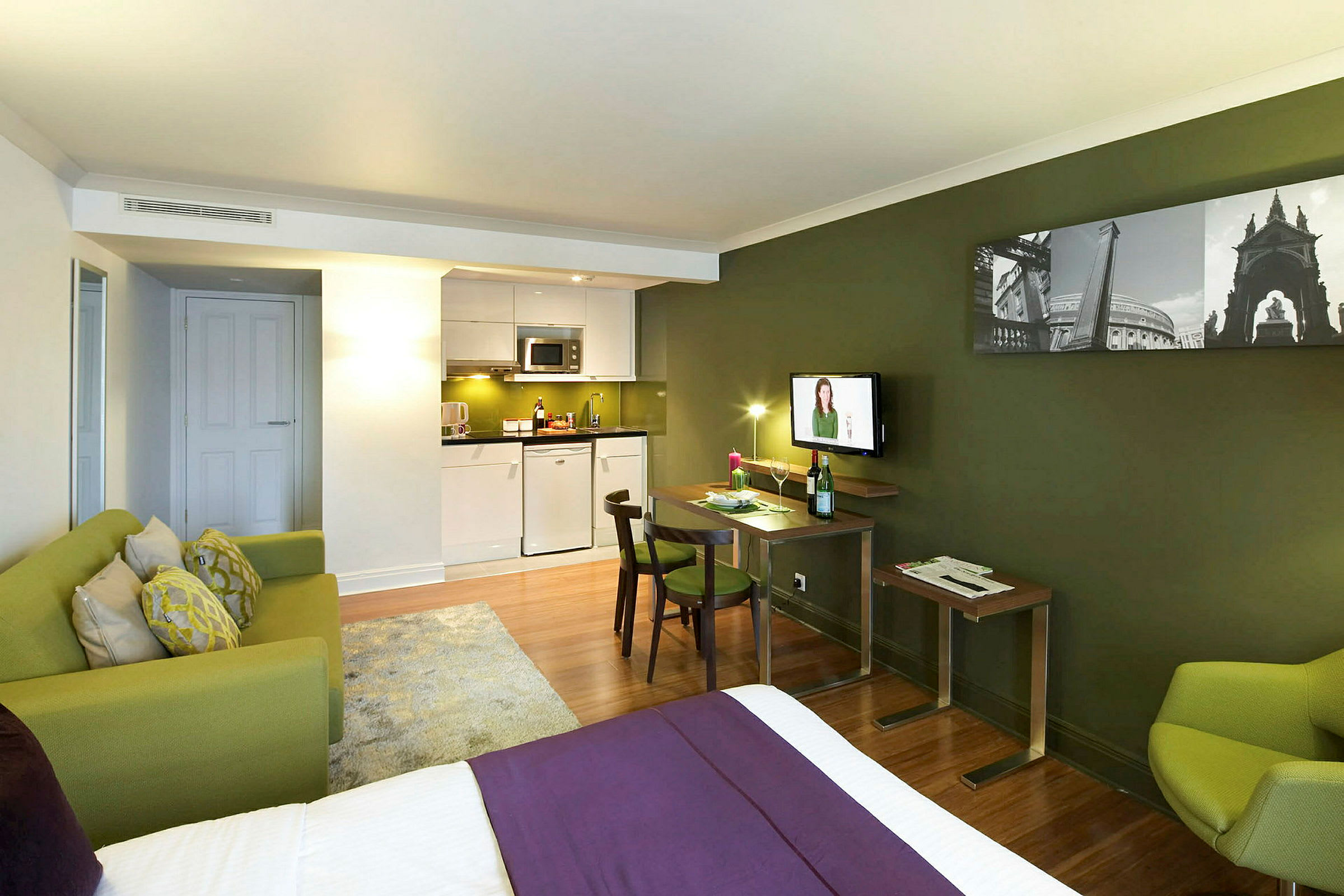 Ett hotellrum med en säng, en sittgrupp och ett kök. (AI-genererad text)