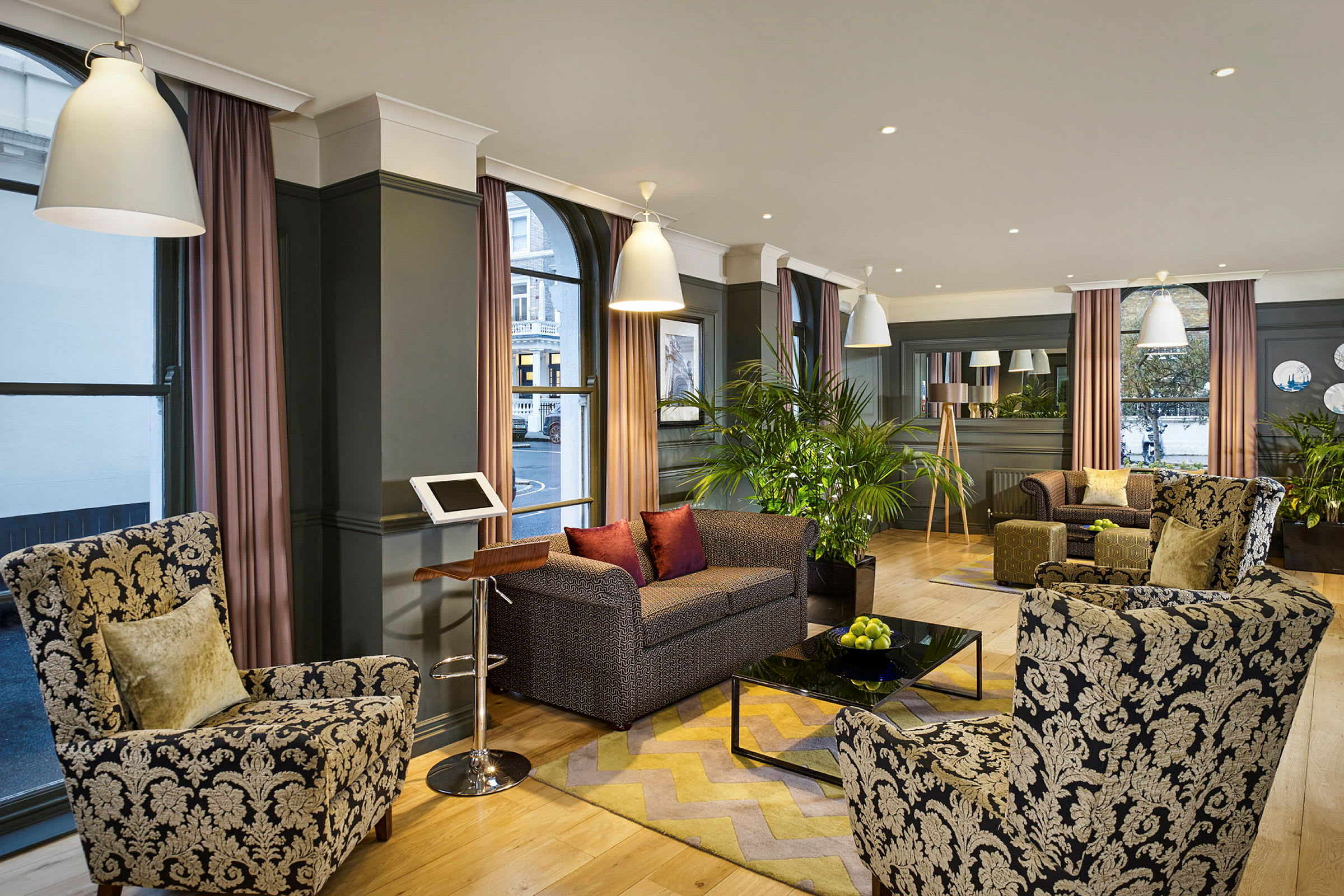 En hotellobby med fåtöljer och soffor omkring ett soffbord samt dekoration med växter. (AI-genererad text)