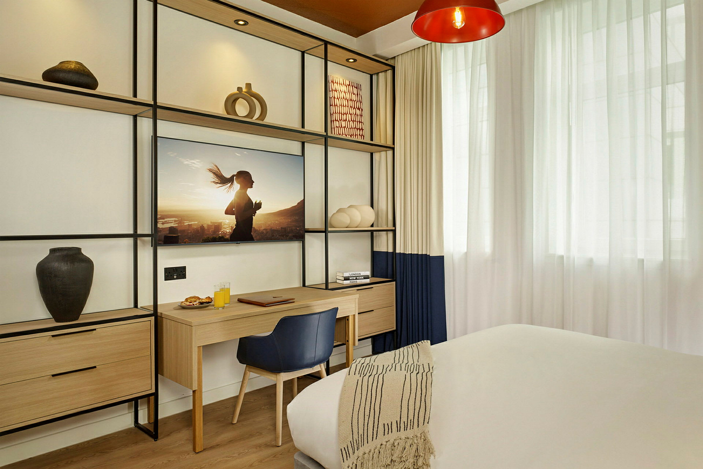 Modernt inrett hotellrum med skrivbord och dekorativa hyllor. (AI-genererad text)