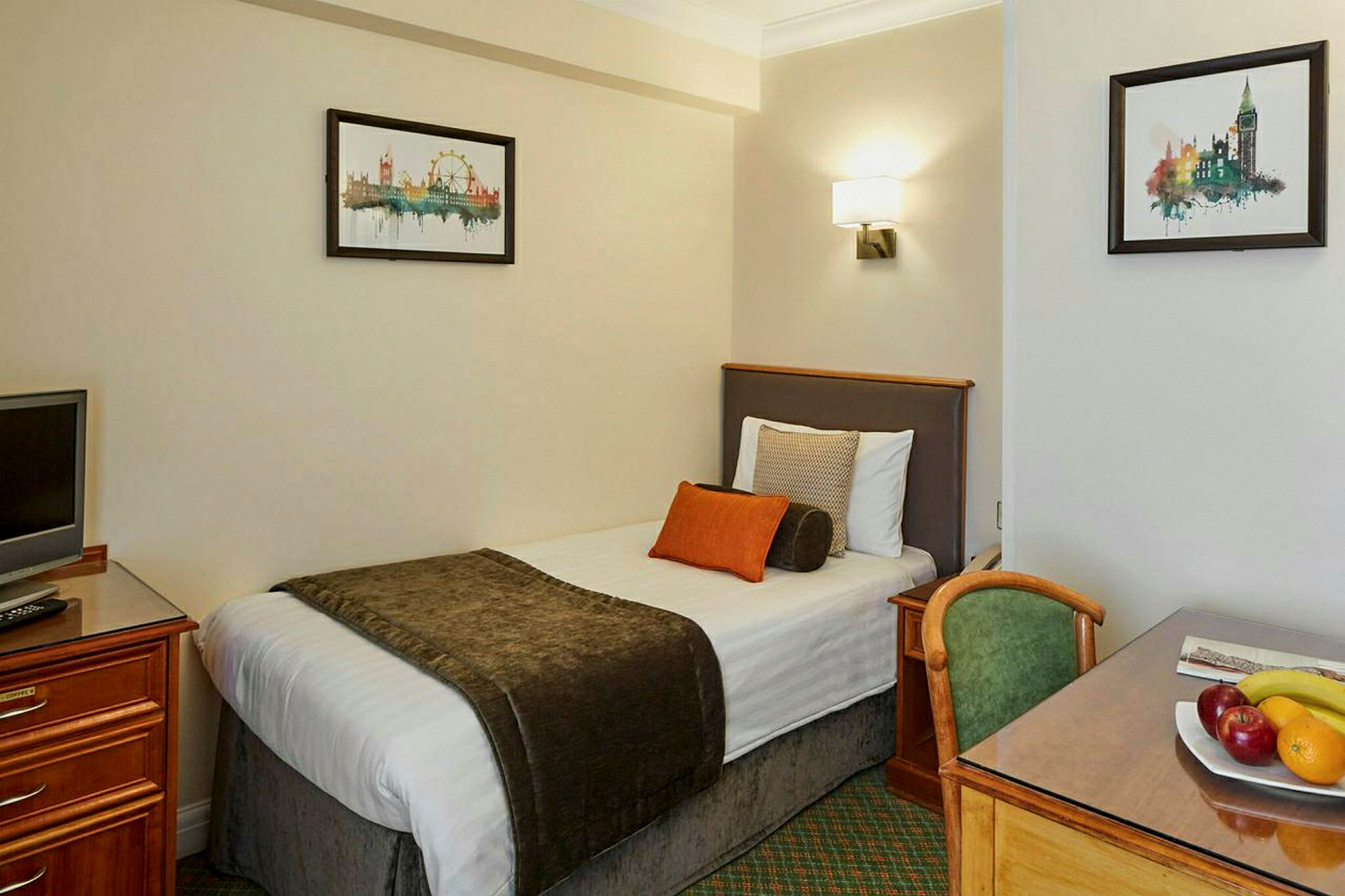 Hotelrum med enkelsäng, skrivbord, stol och dekorativ konst på väggen. (AI-genererad text)