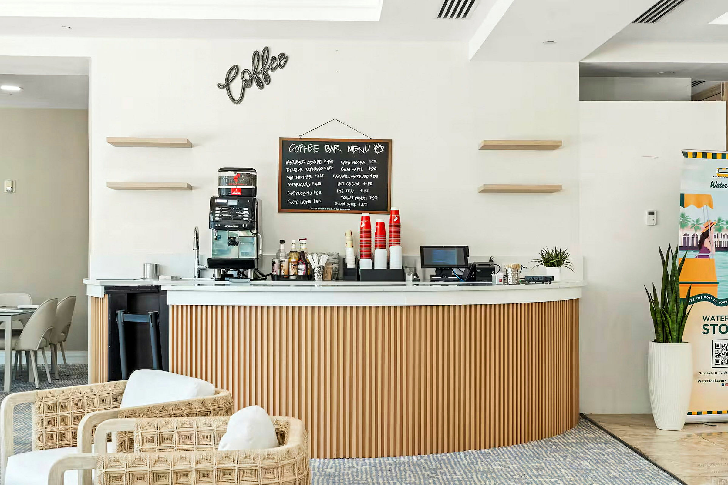 En kaffe-bar med en kaffemaskin, en meny på väggen och koppar och tillbehör på disken. (AI-genererad text)