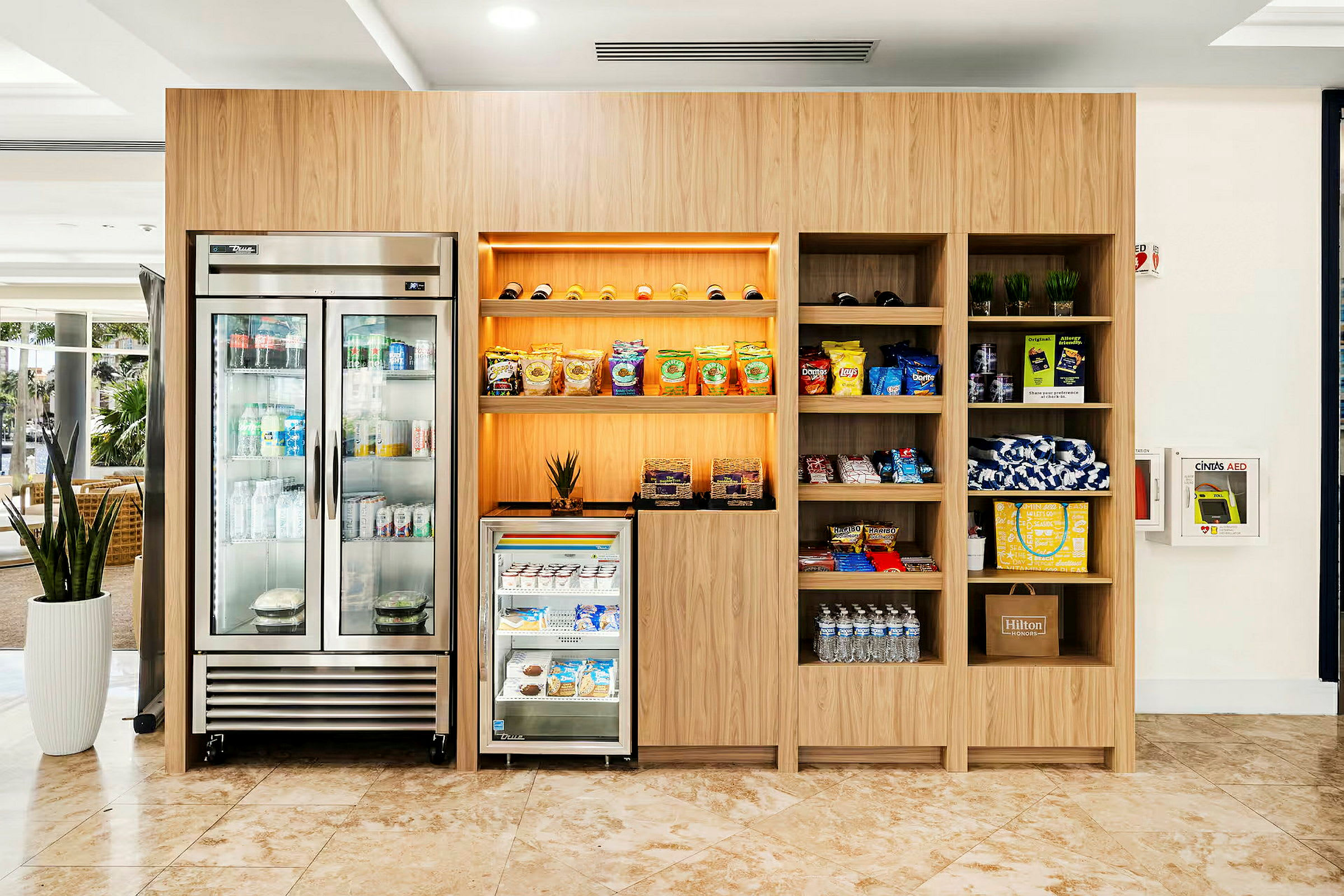 En modern kiosk med ett kylskåp, hyllor med snacks och drycker samt övriga handelsvaror. (AI-genererad text)