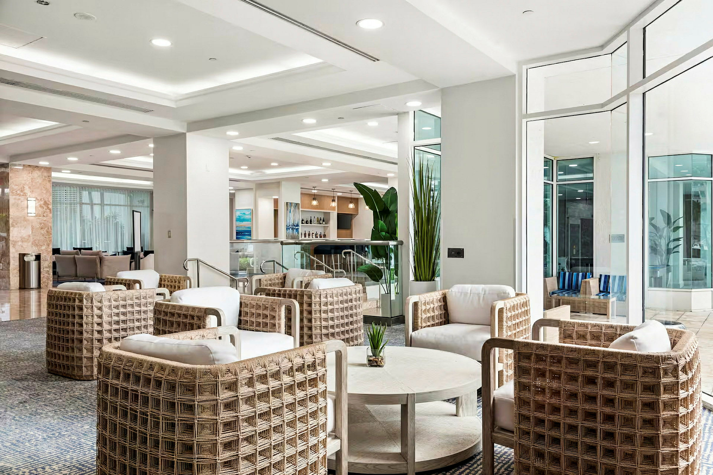 En modern hotellobby med sittgrupper i ljusa färger och stora fönster. (AI-genererad text)