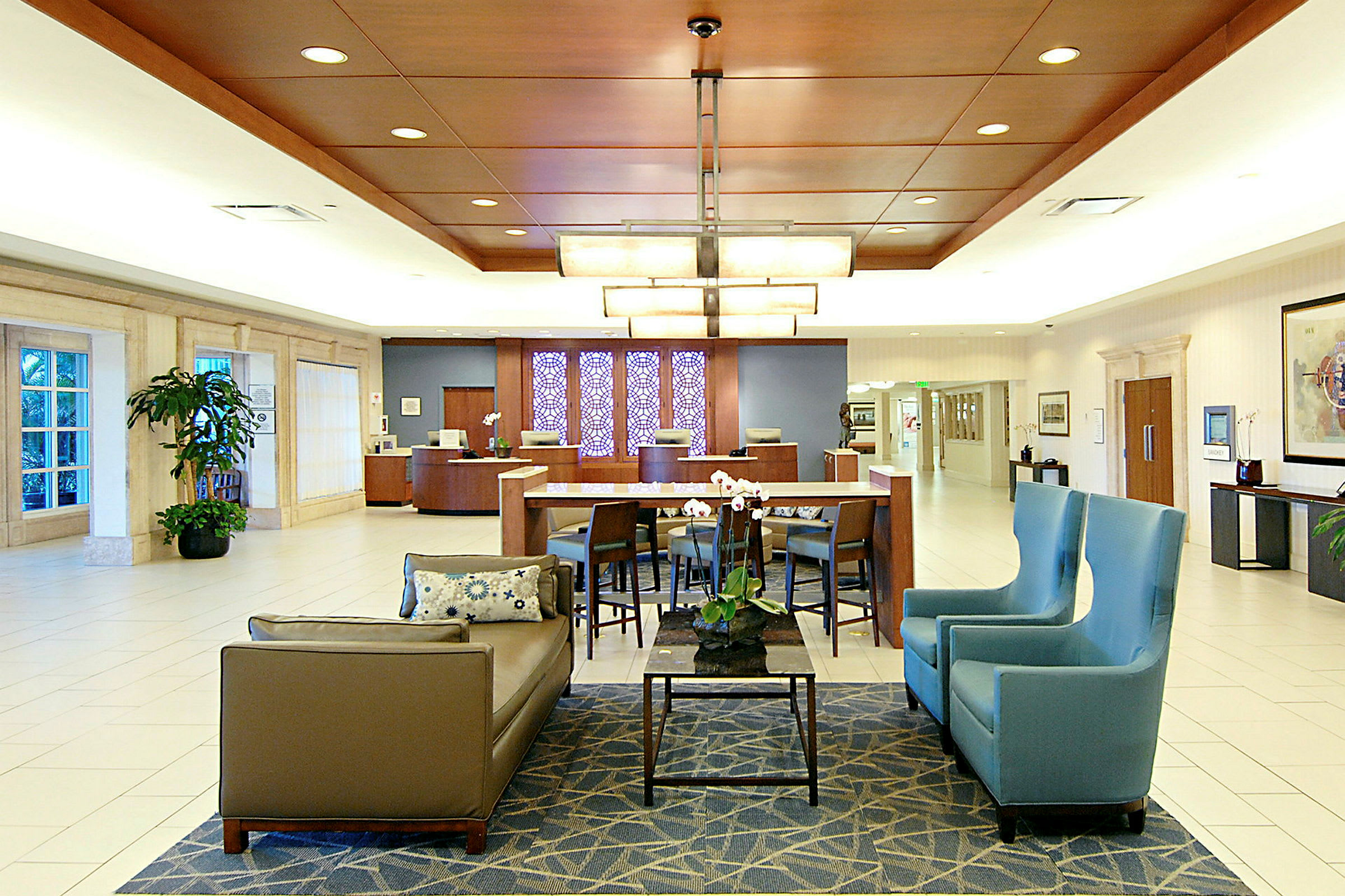 Hotellobby med sittgrupper, bord, växter och receptionsdisk. (AI-genererad text)