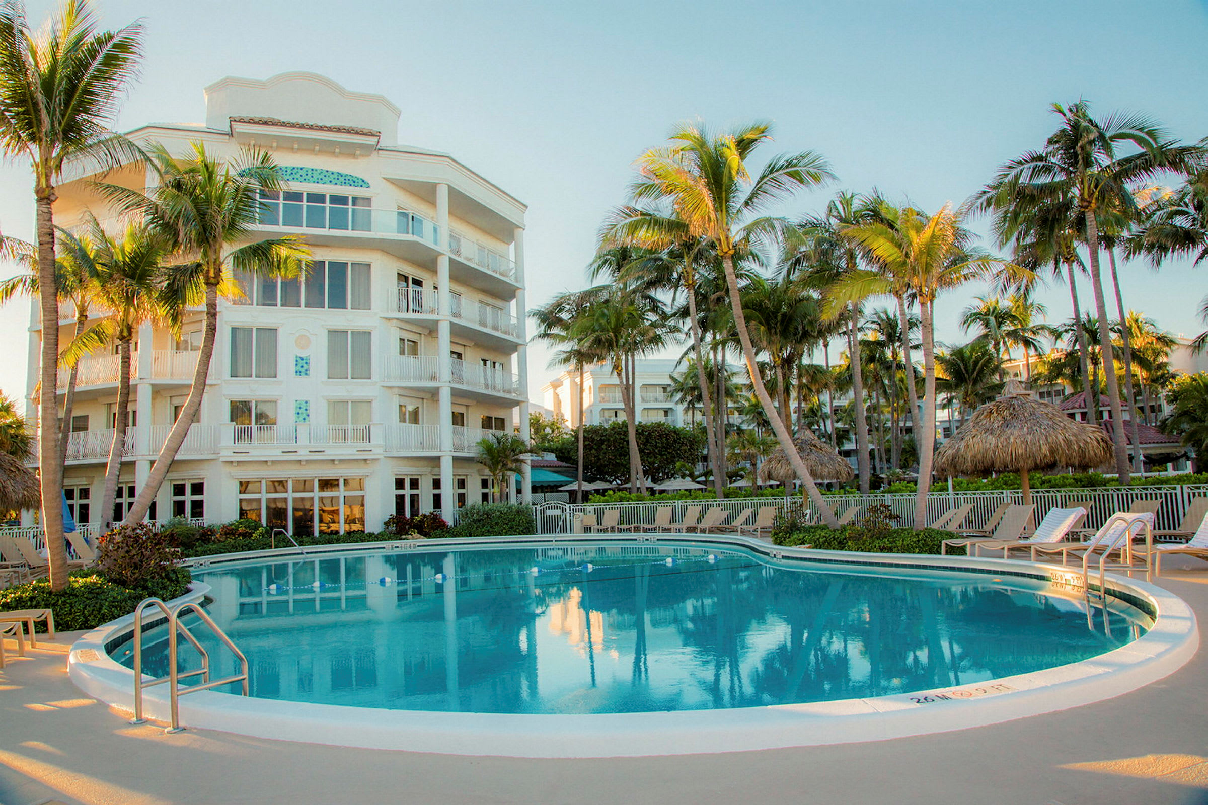 Hotellbyggnad vid en pool omgiven av palmer. (AI-genererad text)