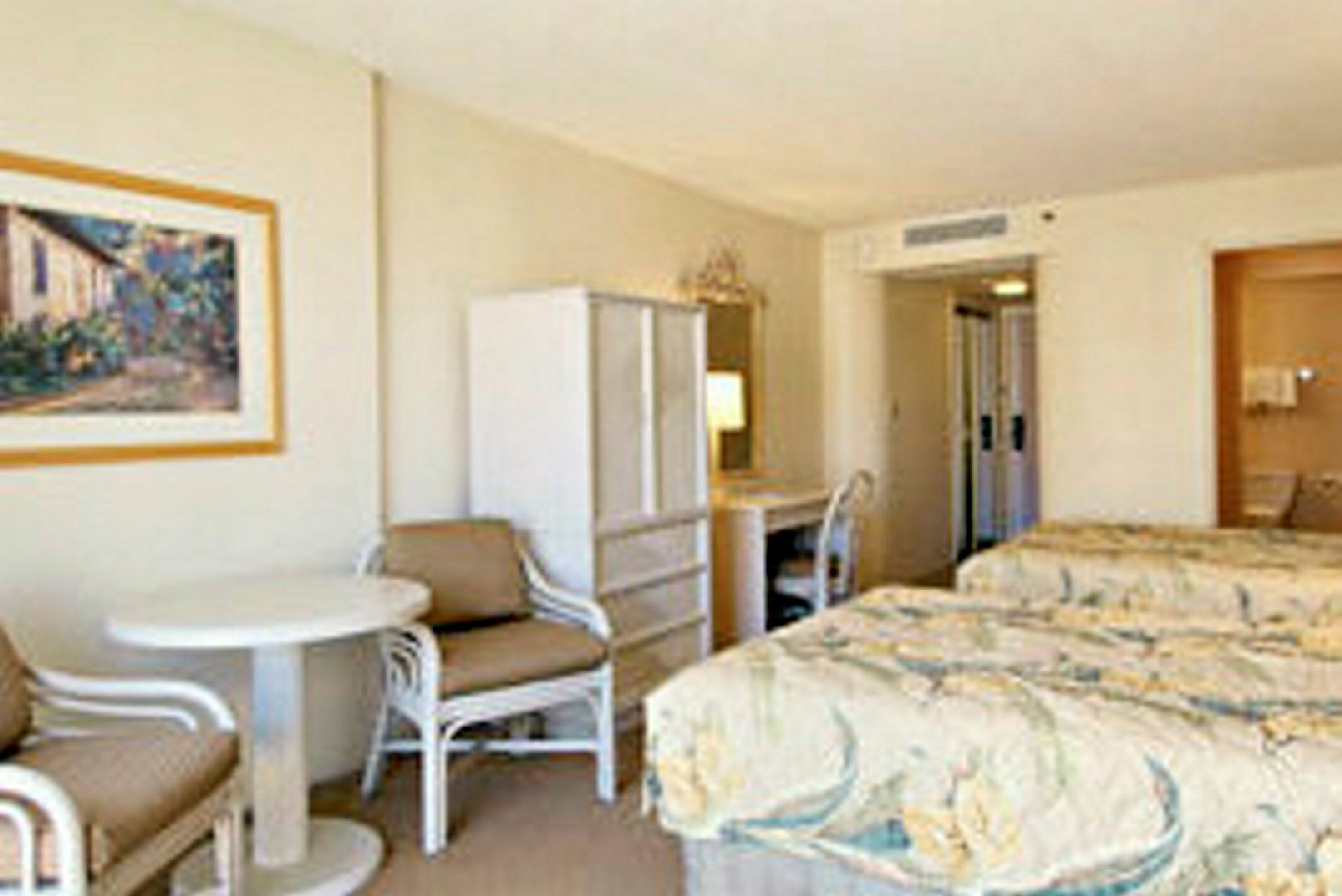 Hotellrum med två sängar, ett litet bord med stolar och en garderob. (AI-genererad text)