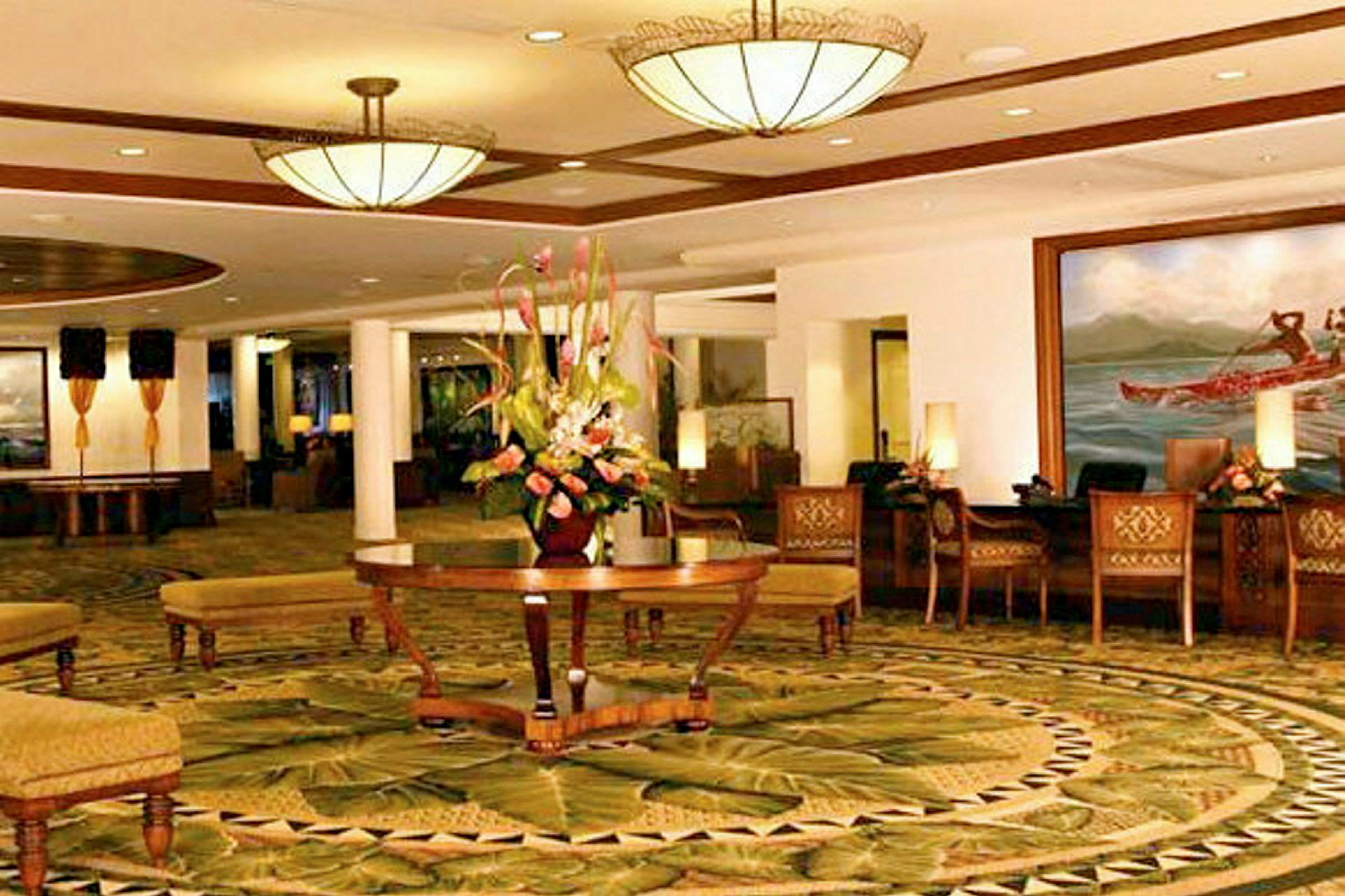 Ett elegant hotellobby med dekorativa mattor, en central blombukett och bekväma sittmöbler. (AI-genererad text)
