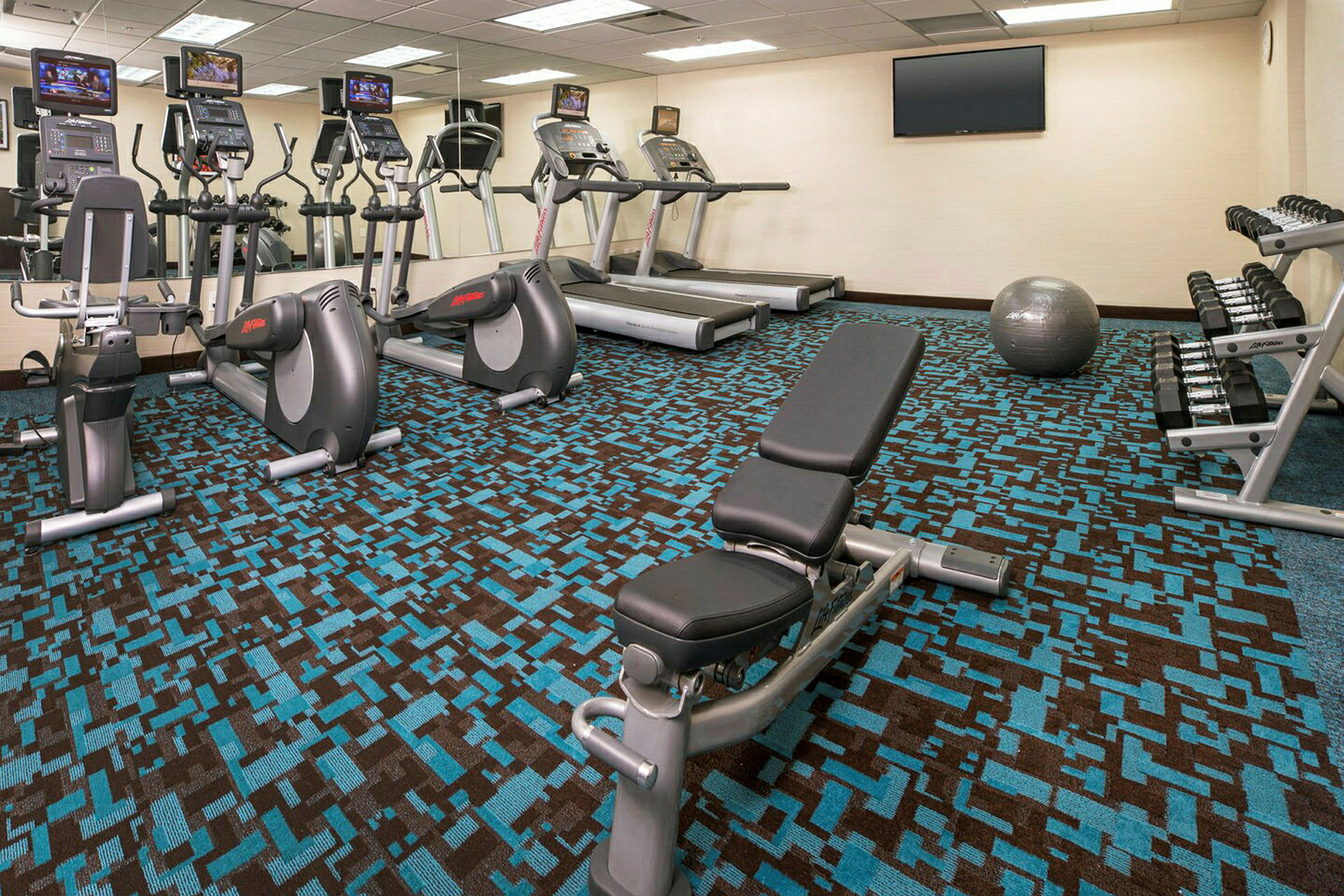 Gym med träningsmaskiner, vikter, bänk och träningsboll. (AI-genererad text)