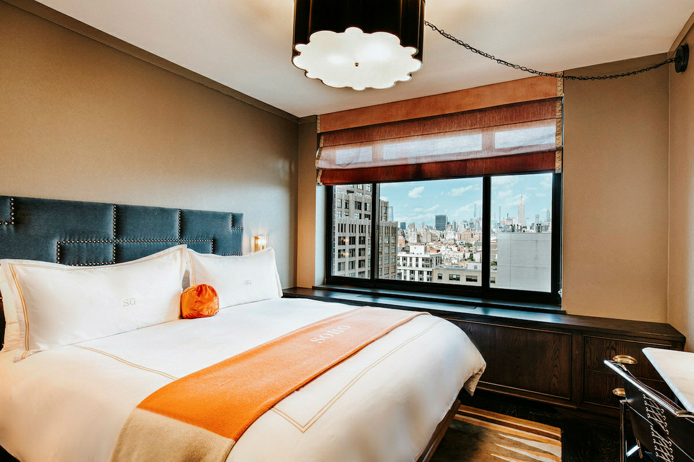 Ett elegant hotellrum med en säng, stora fönster och stadsvy. (AI-genererad text)