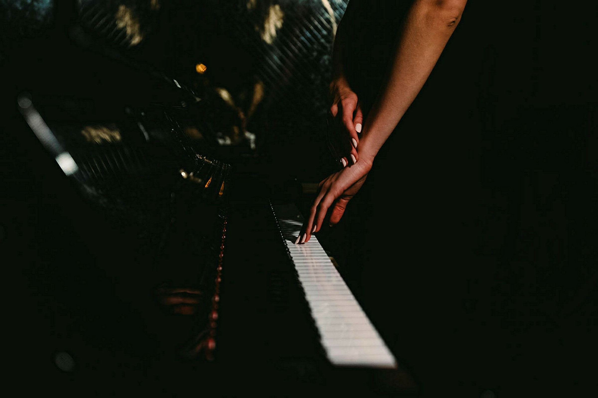 En hand placerad på ett piano i ett mörkt rum. (AI-genererad text)