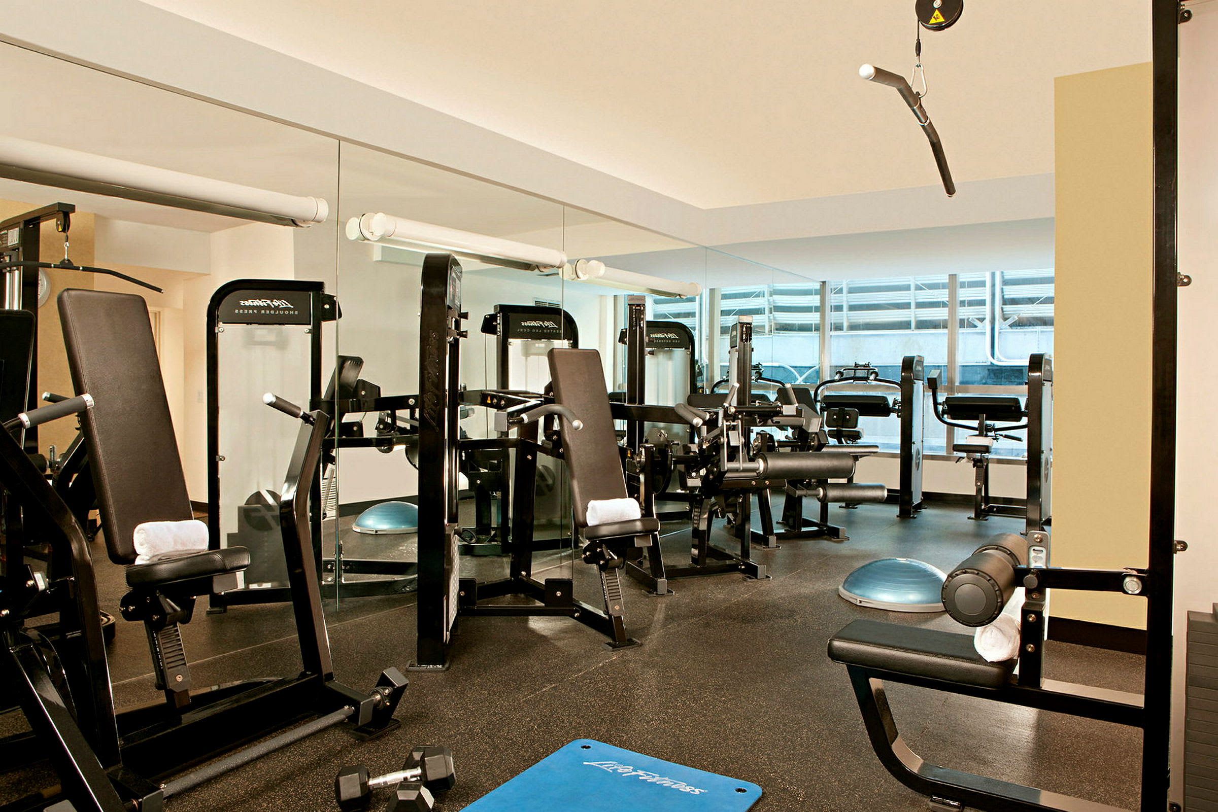 Ett gym med träningsmaskiner, spegelväggar och träningsutrustning. (AI-genererad text)
