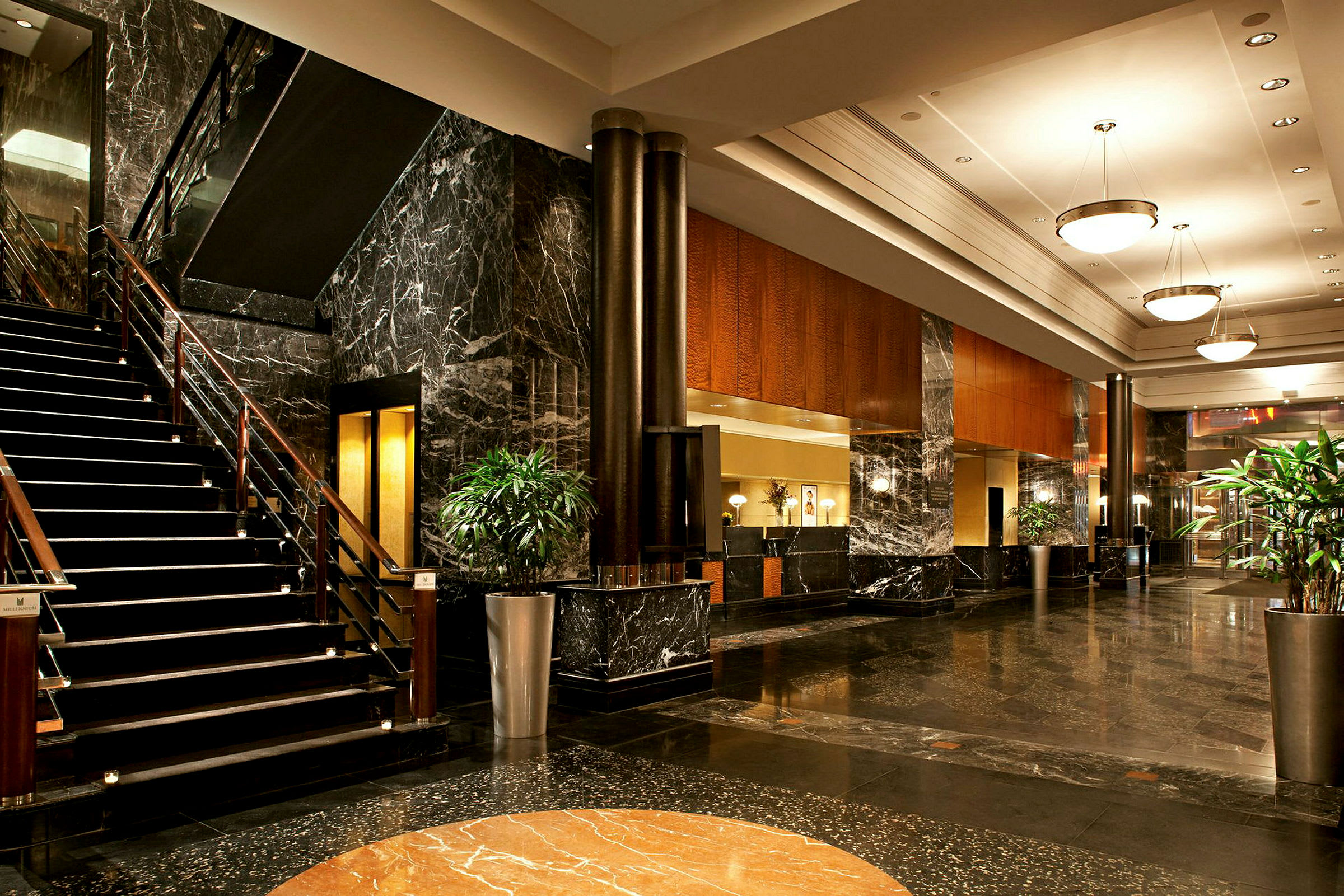 Bild på en hotellets lobby med marmorgolv, en trappa, soffor och växtarrangemang. (AI-genererad text)