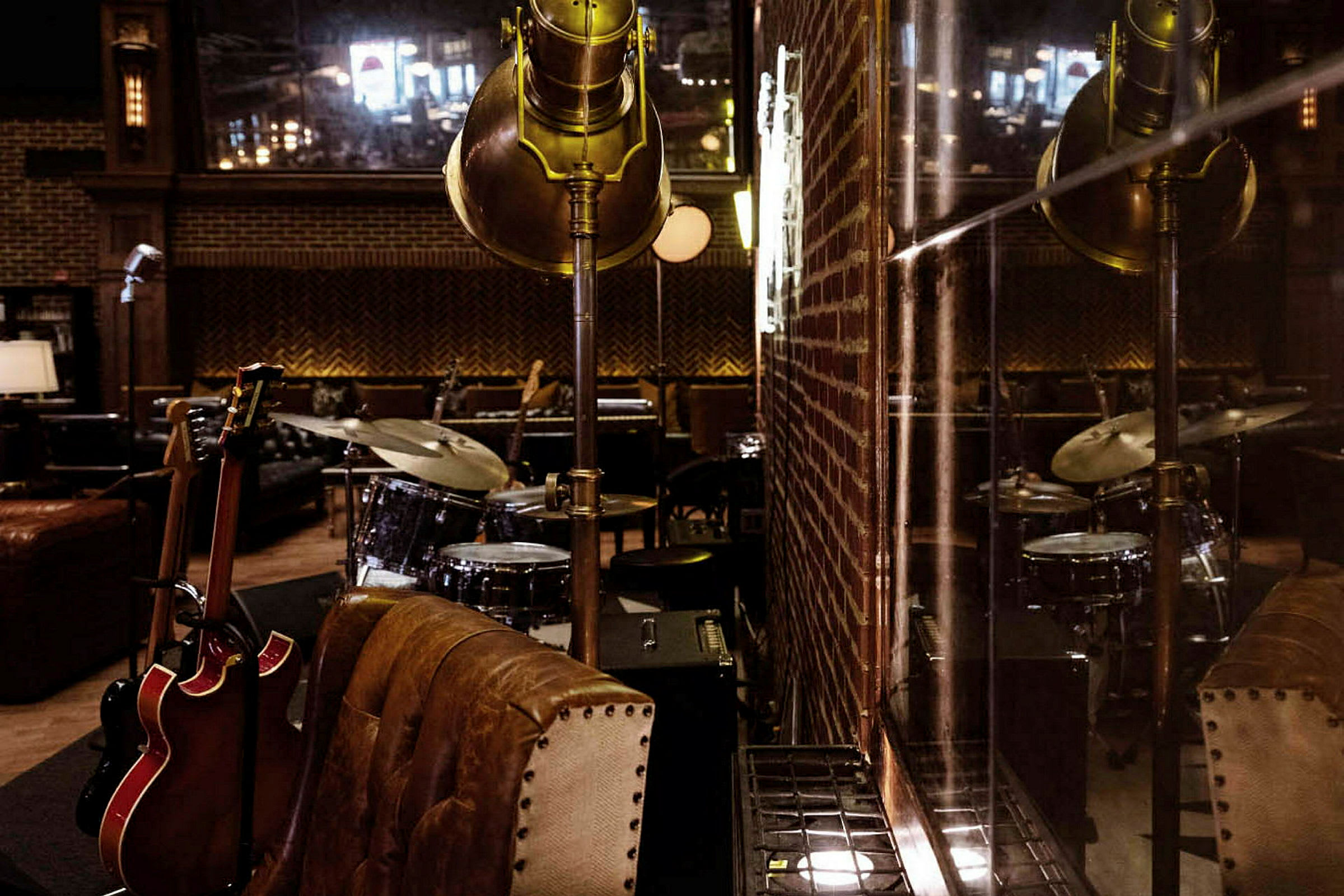 Ett rum dekorerat med musikinstrument inklusive en trumma och gitarrer, samt möbler och en tegelvägg. (AI-genererad text)