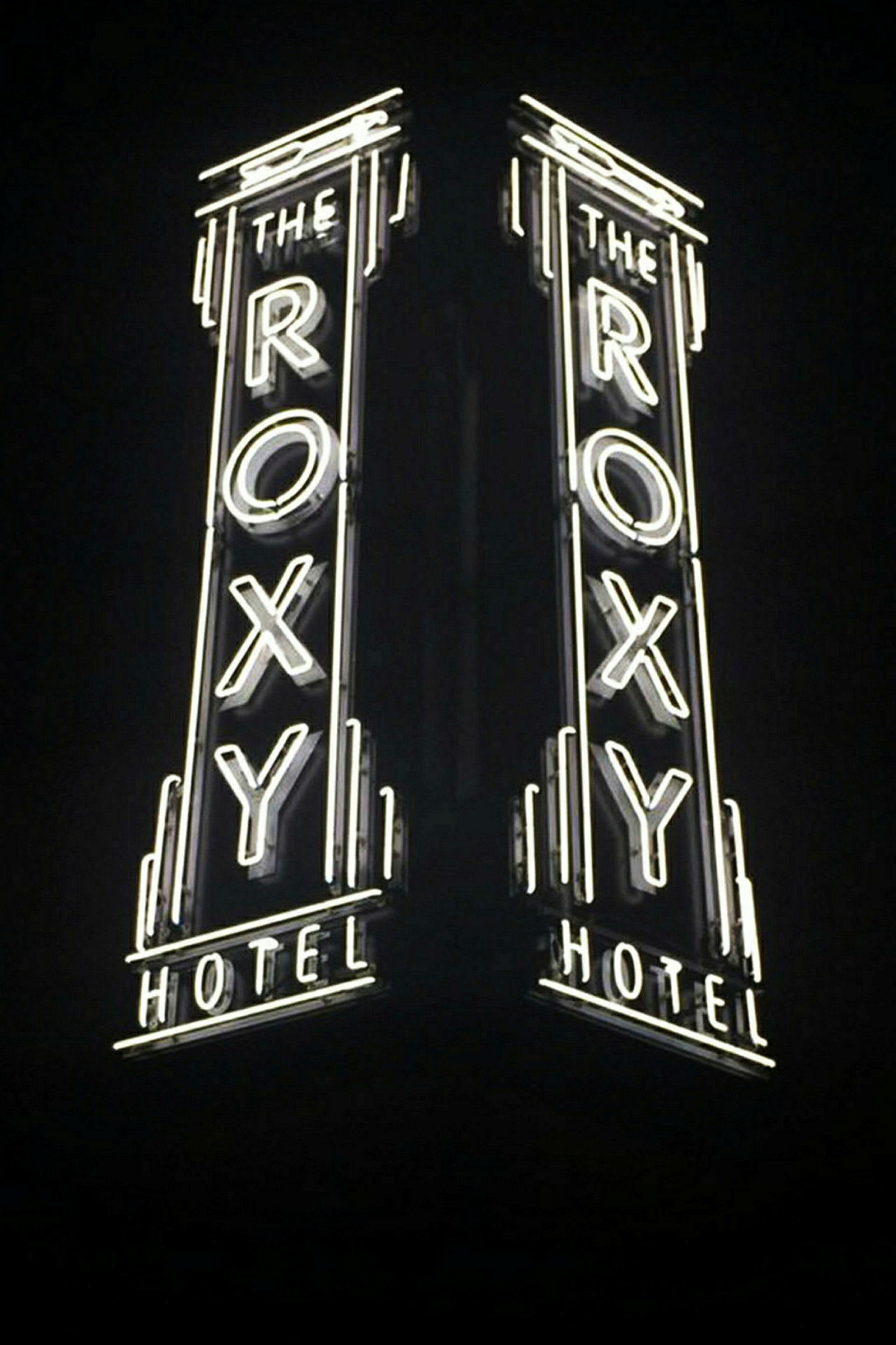 En neonskylt med texten "The Roxy Hotel" som lyser i mörkret. (AI-genererad text)