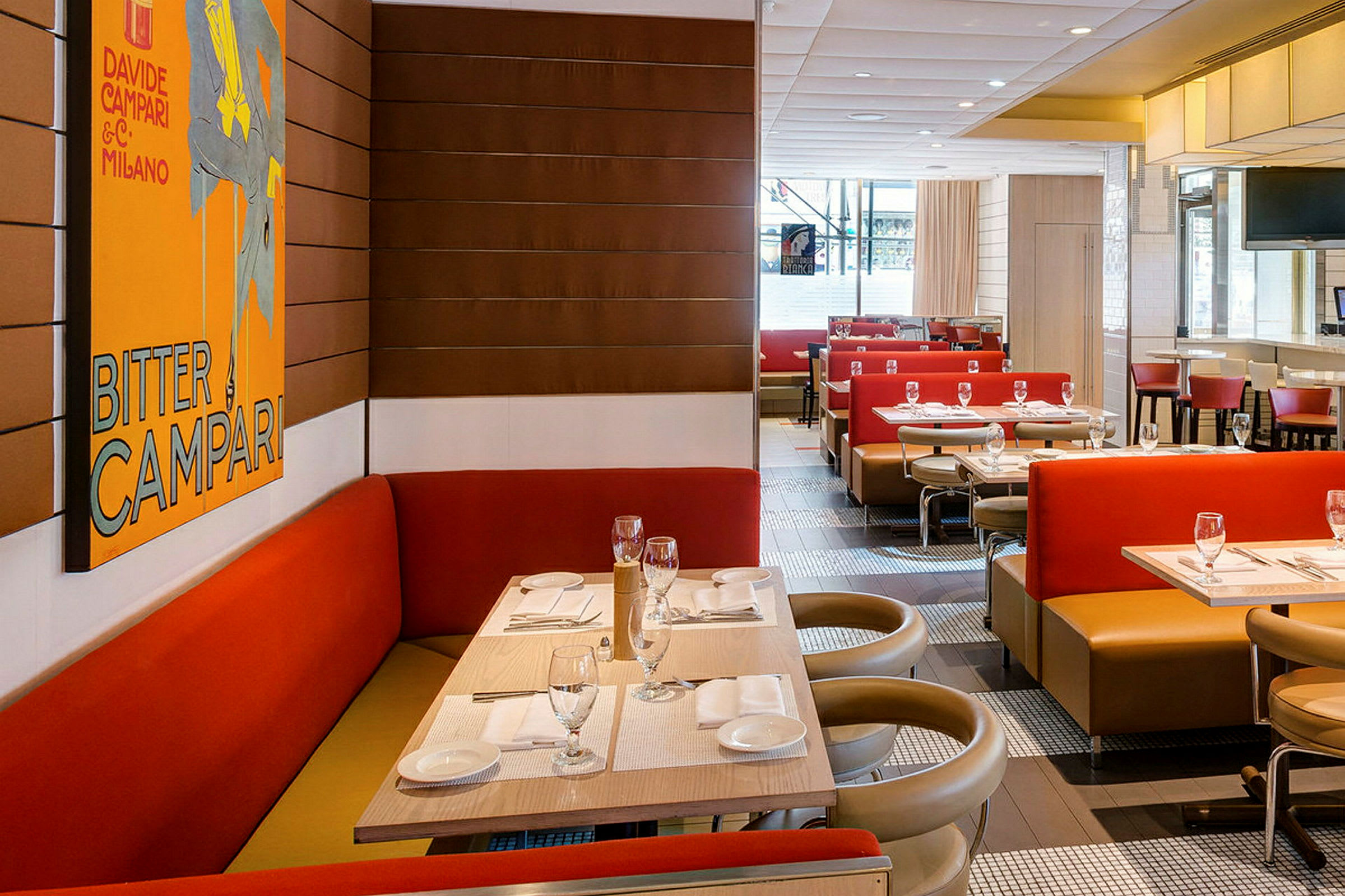 Inredning av en restaurang med röda och beige sittplatser samt ett väggmonterat konstverk. (AI-genererad text)
