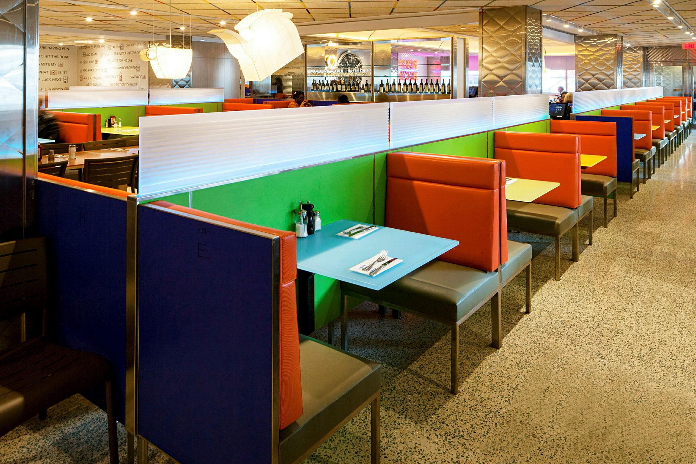 Färgglada bås med bord och stolar i en restaurang. (AI-genererad text)