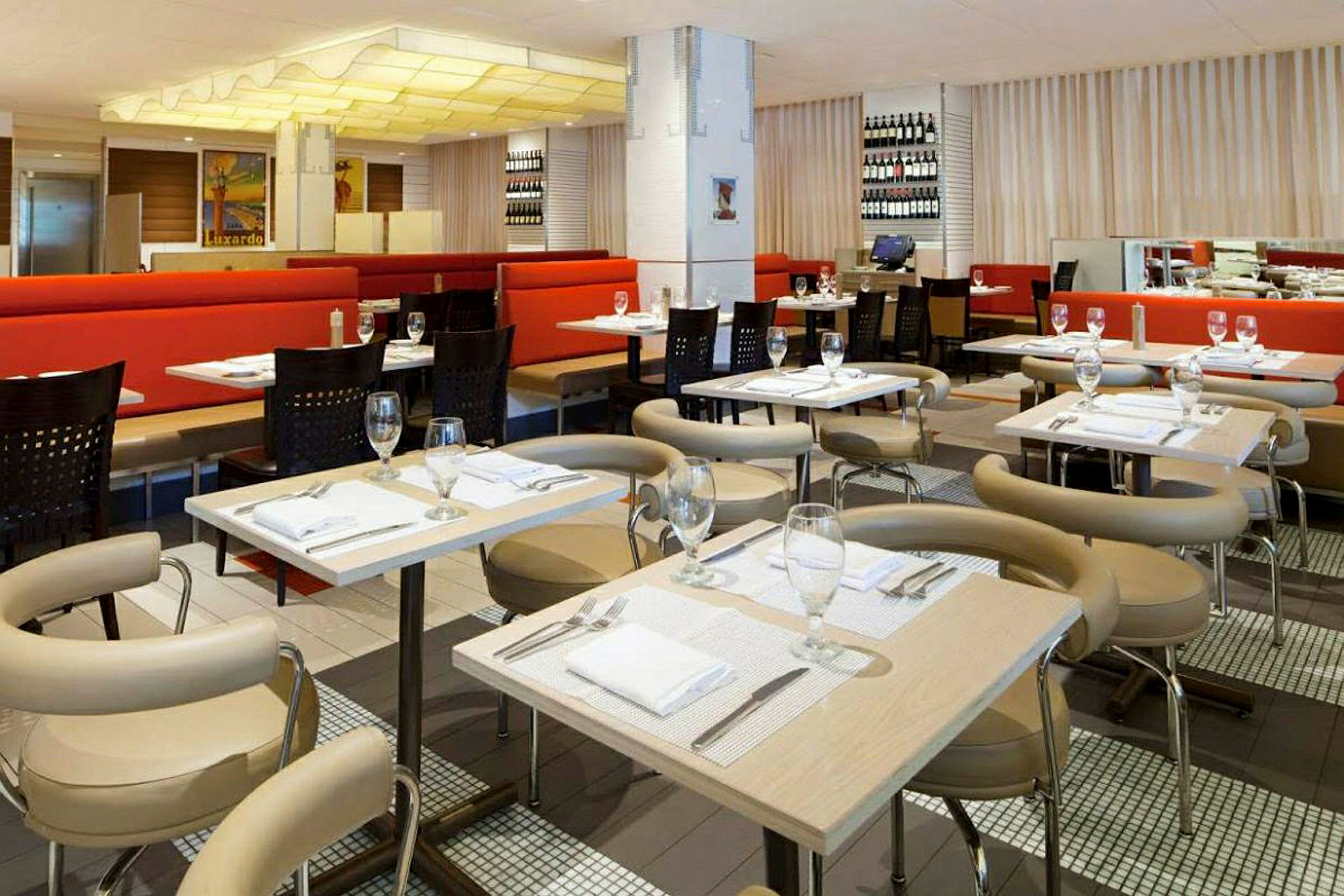 Interiör av en restaurang med dukade bord och stolar, röda soffor och dekorationer på väggarna. (AI-genererad text)