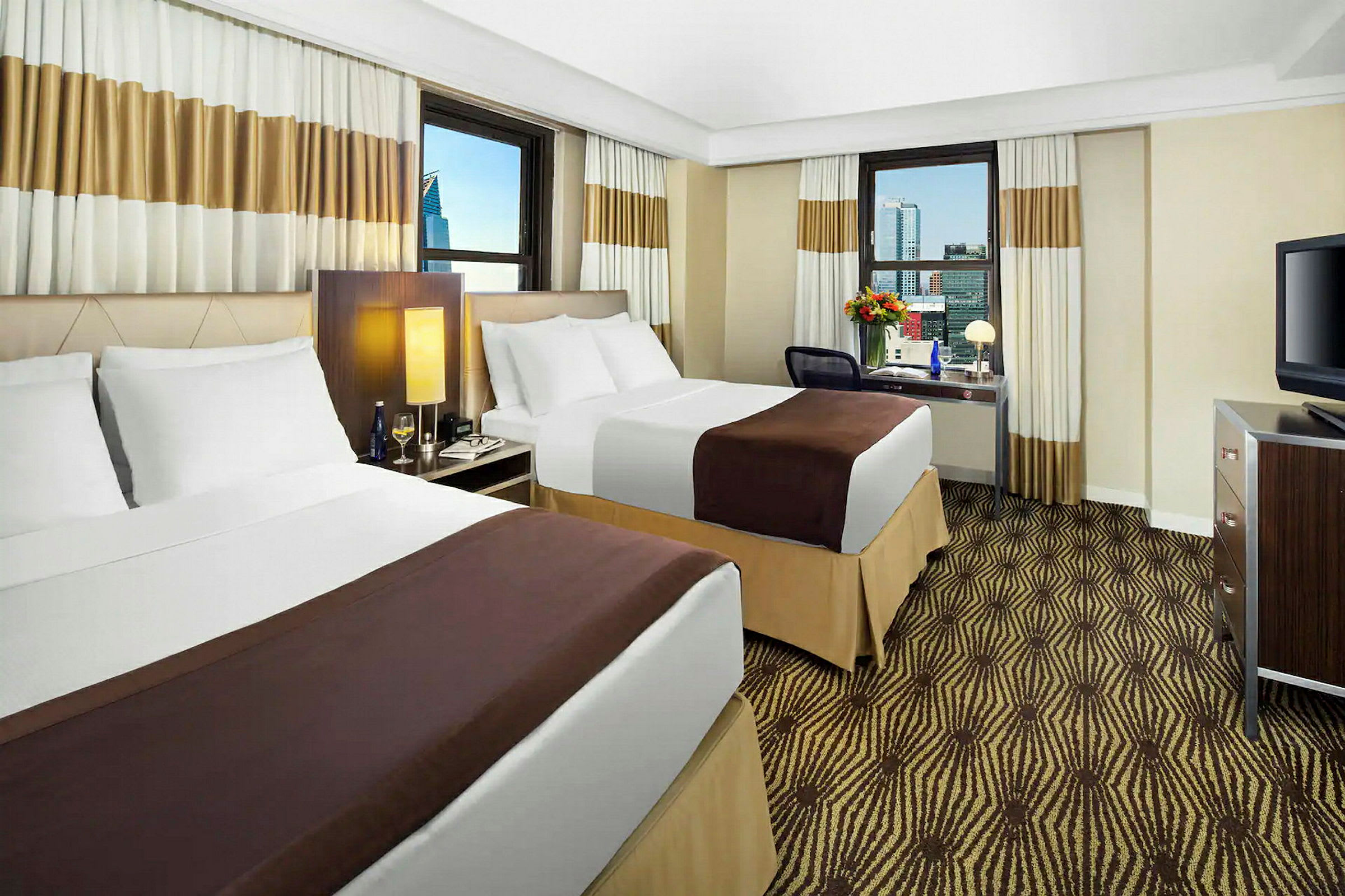 Ett hotellrum med två sängar, en tv och ett skrivbord med stol. (AI-genererad text)
