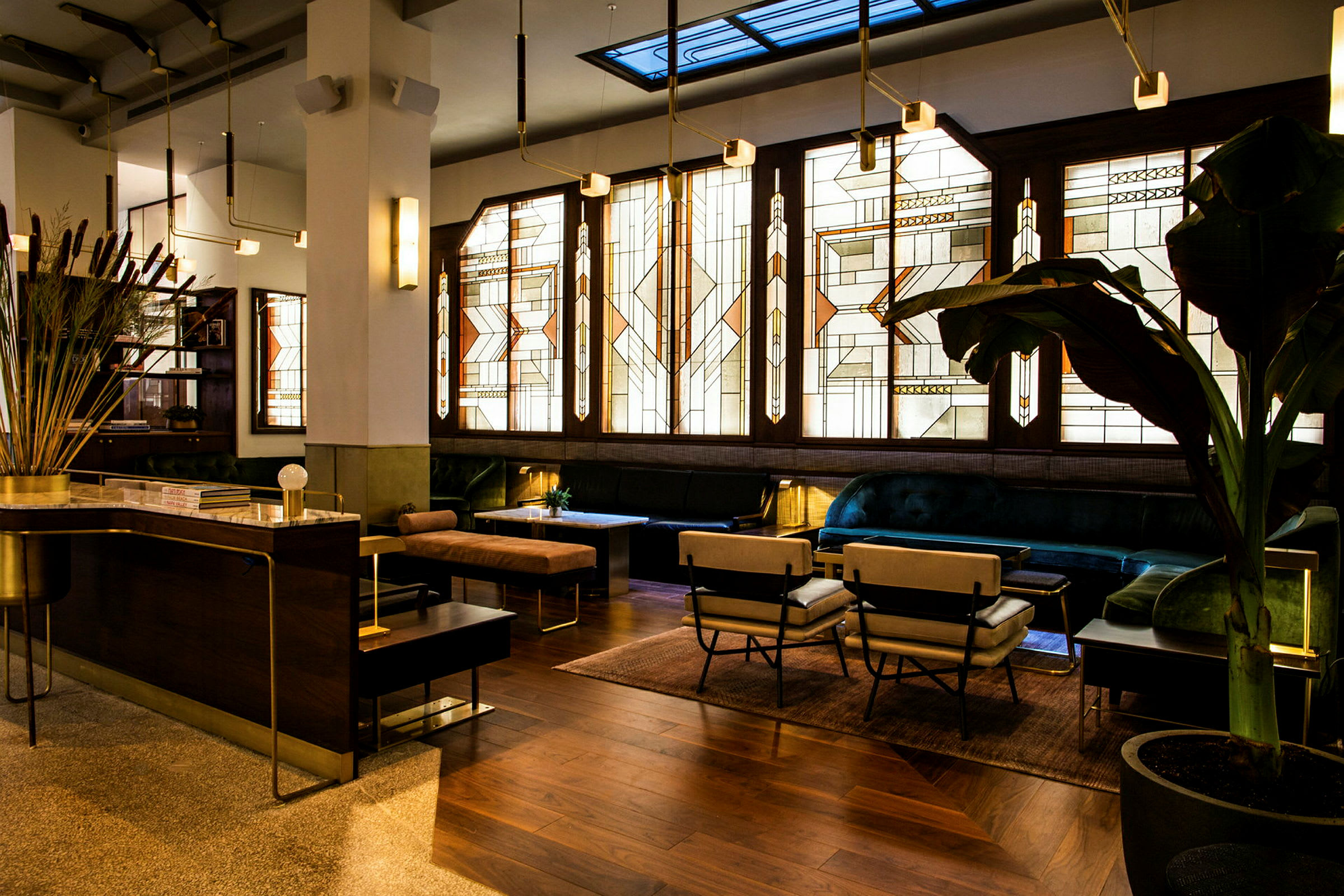 Ett elegant inrett rum med art déco-inspirerade glasfönster, bekväma sittmöbler och ett receptionområde. (AI-genererad text)