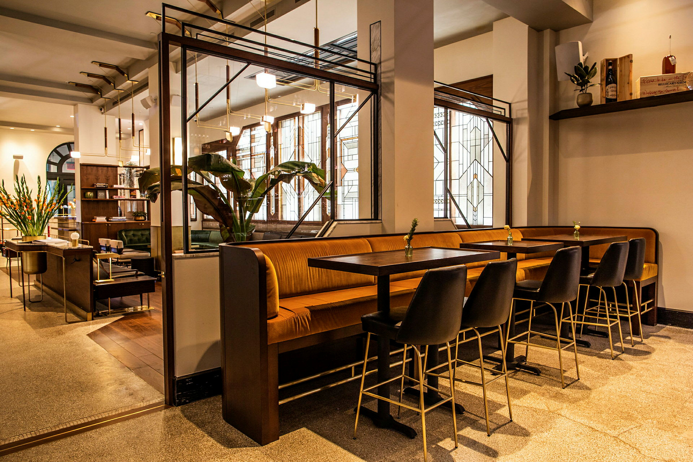 Ett modernt kafé med bord, stolar och bänkar samt dekorativa gröna växter och stilfull belysning. (AI-genererad text)