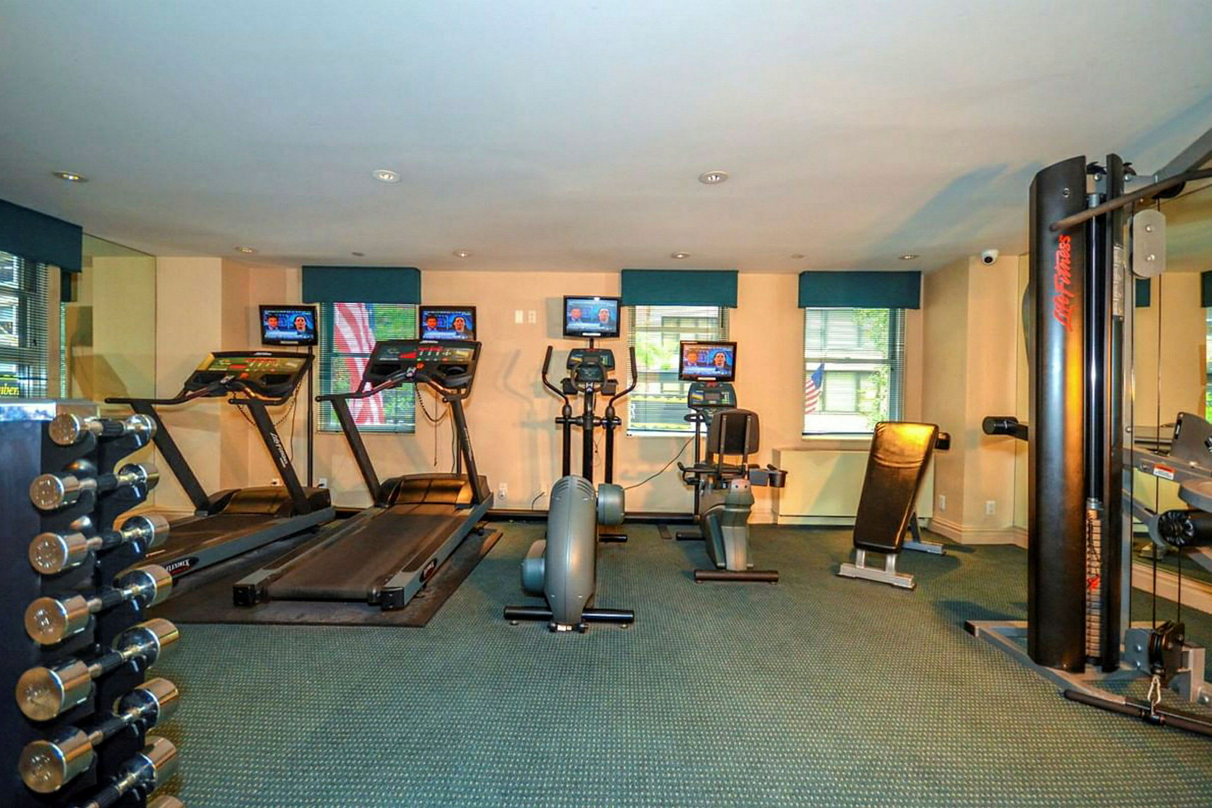 Bild av ett gym med träningsmaskiner som löpband, motionscyklar och styrketräningsutrustning. (AI-genererad text)