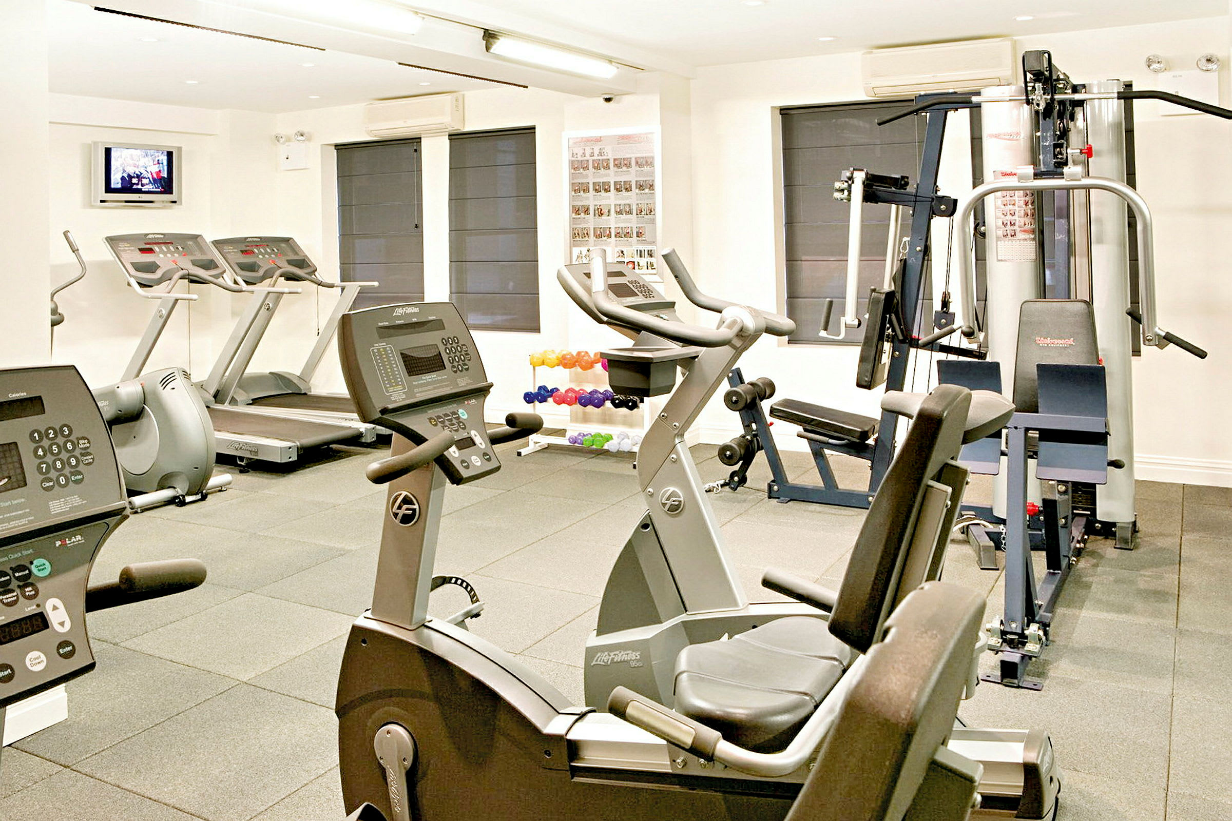 Bild av ett gym med olika träningsmaskiner såsom löpband, motionscyklar och styrketräningsutrustning. (AI-genererad text)