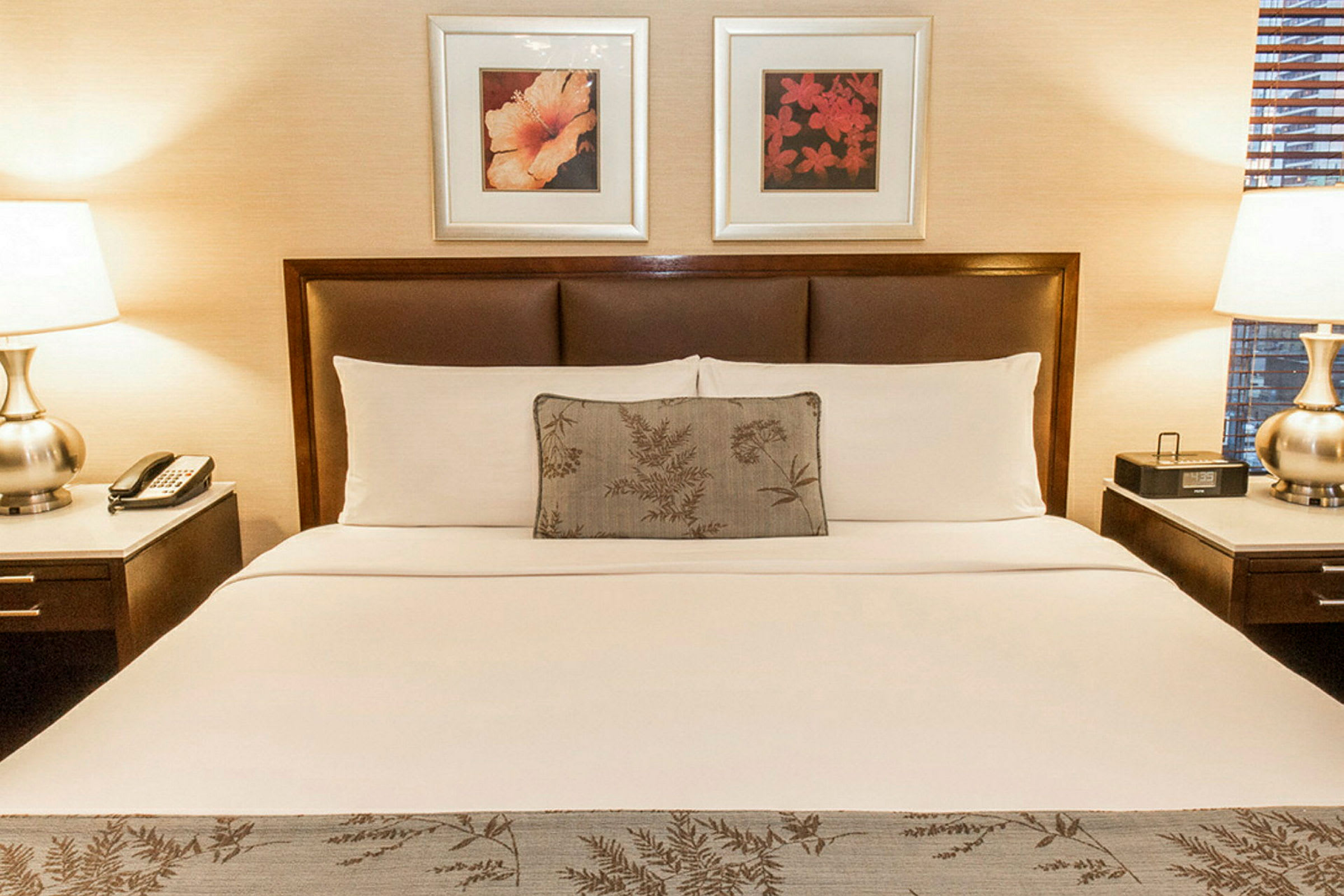 Hotellsäng med dubbla sängbord och två tavlor på väggen. (AI-genererad text)